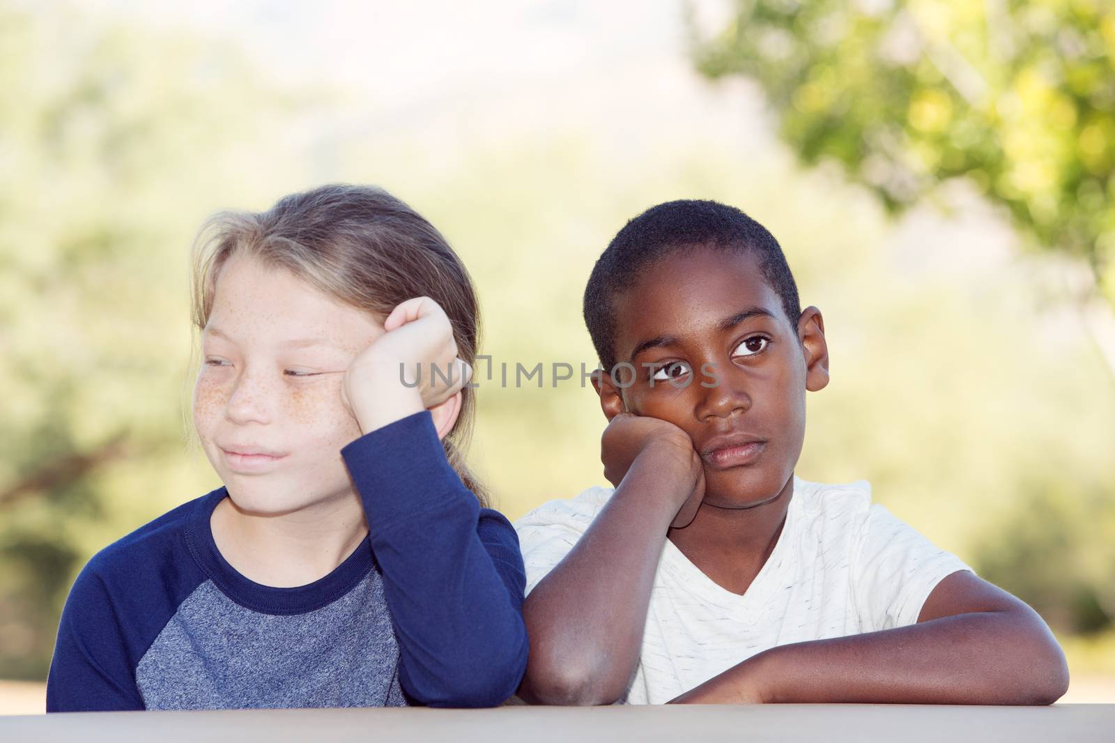 Two bored adopted brothers sitting with hands on cheek waiting for something