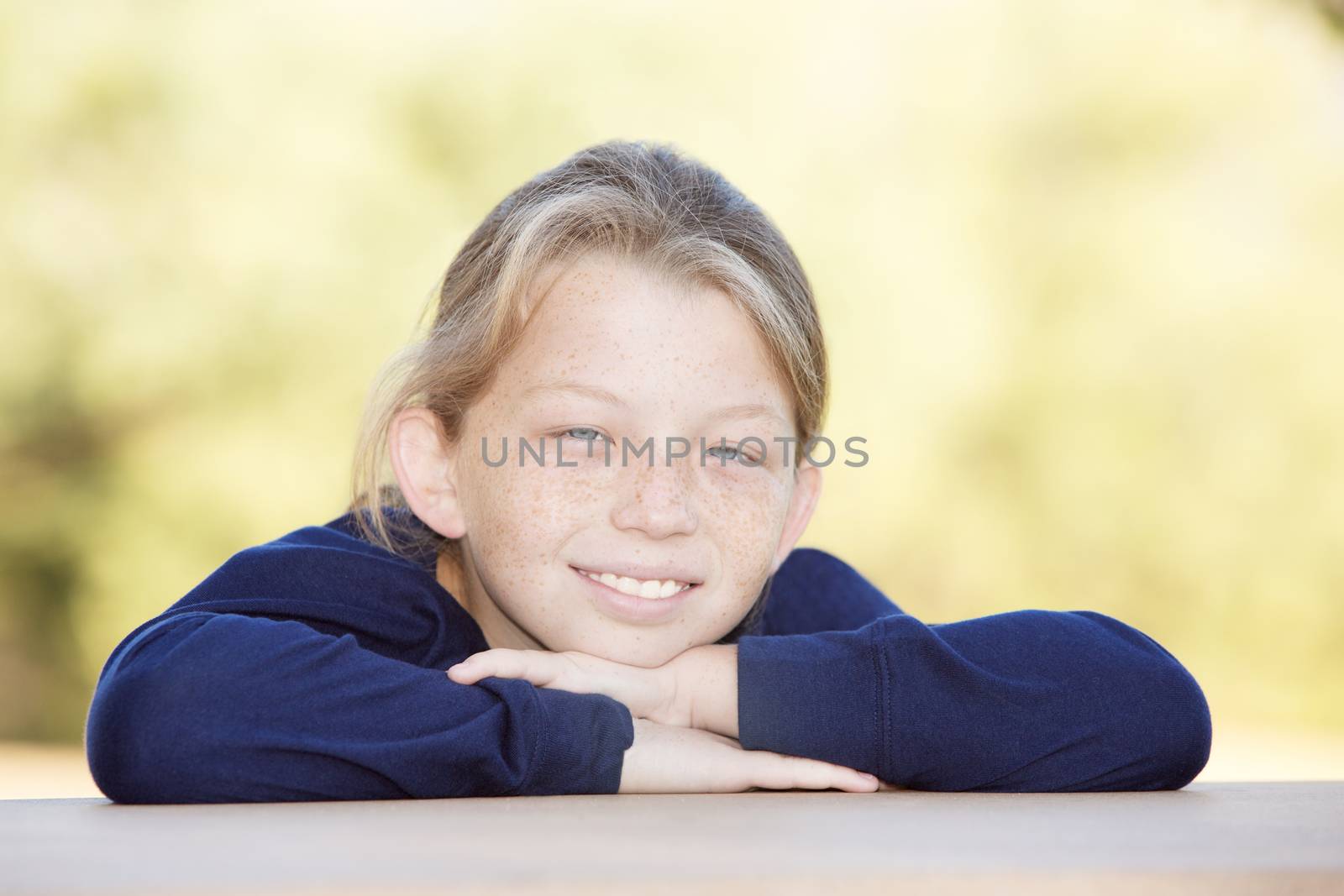 Relaxing single freckled boy with chin on arms outside