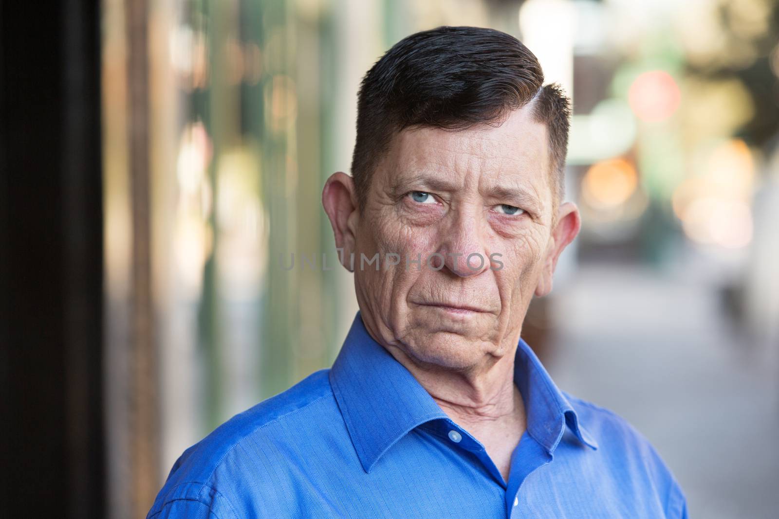 Serious transgender man in blue shirt outside in urban setting