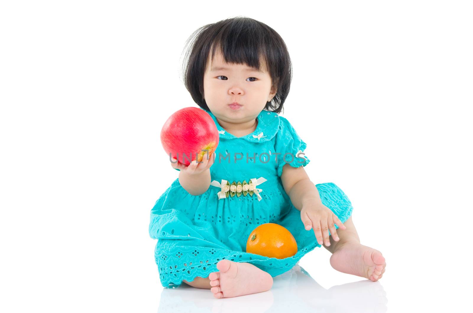 Lovely asian baby girl eating apple and orange