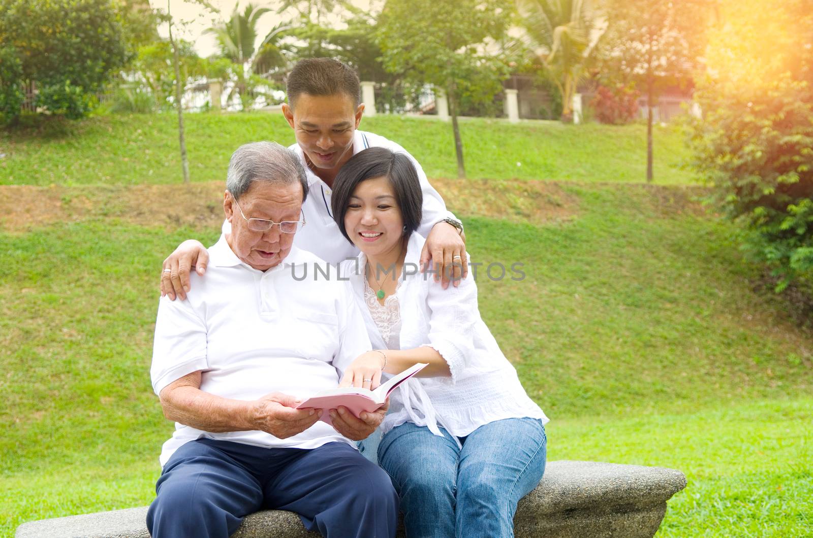 Asian family reading book at outdoor park