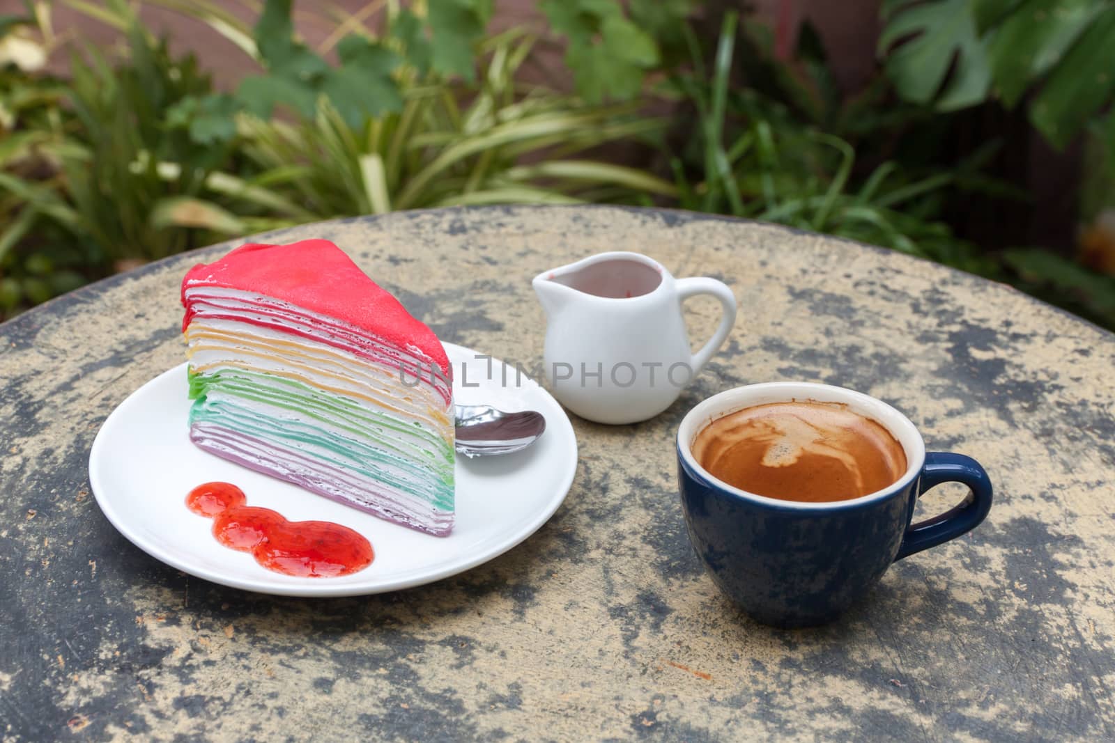 crape cake rainbow and hot espresso coffee in garden side home. crape cake with strawberry sauce