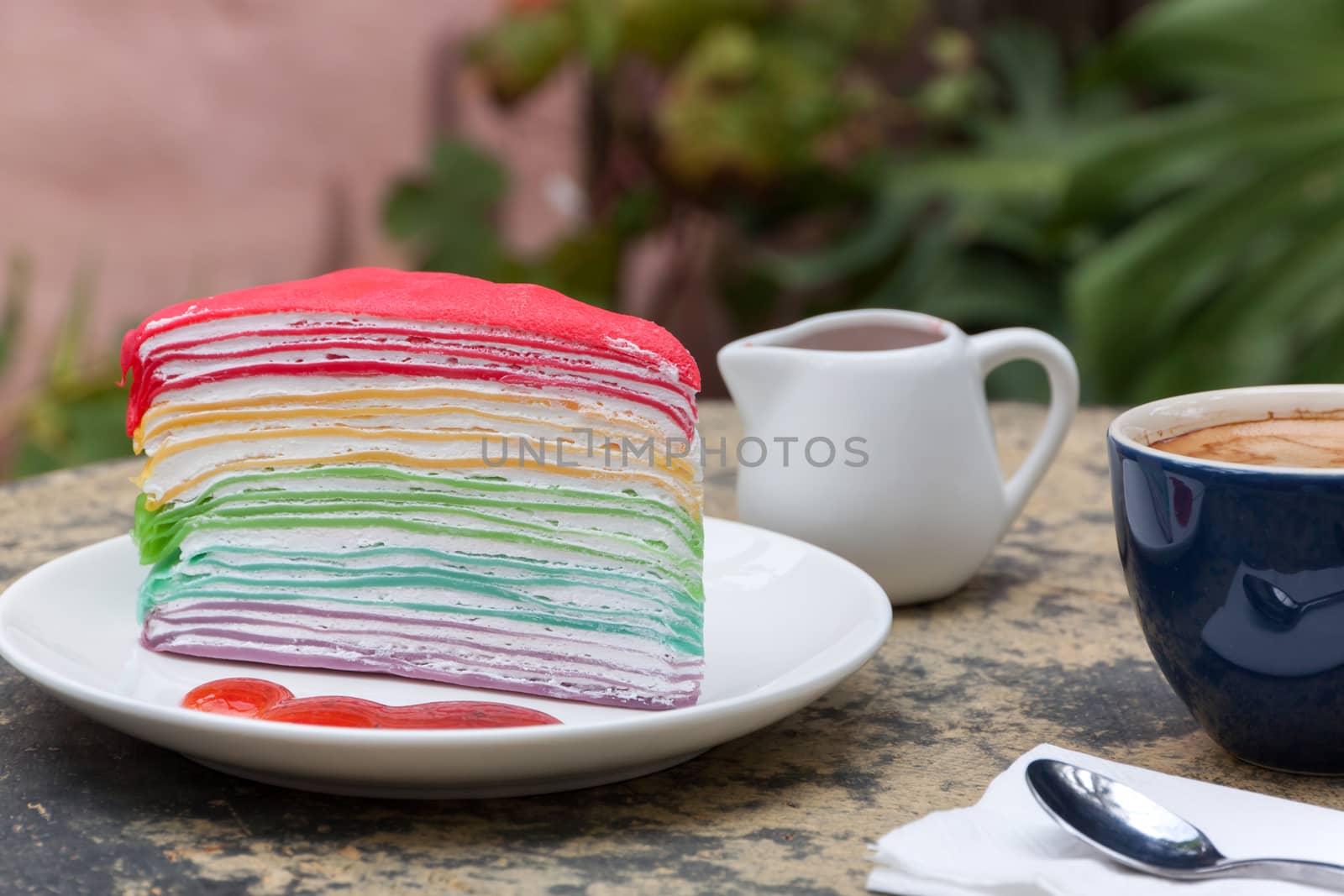 crape cake rainbow and hot espresso coffee in garden side home. crape cake with strawberry sauce