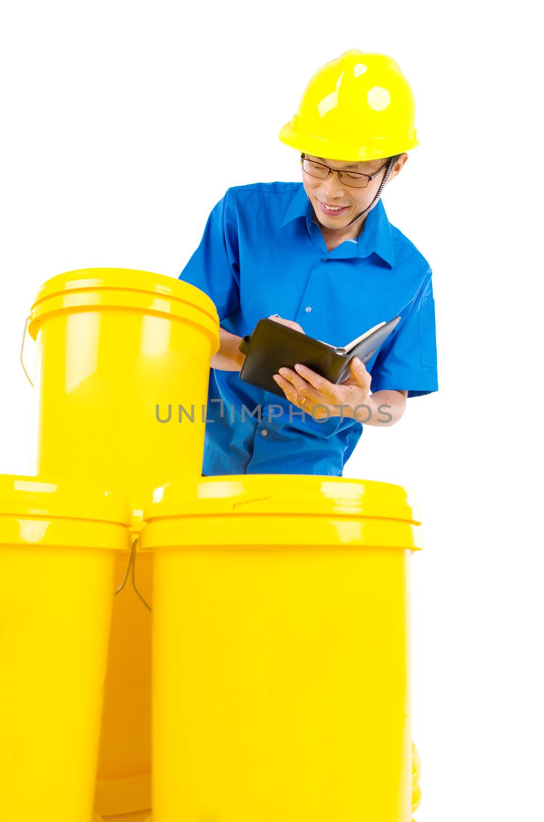 Production worker perfoming stock check on the buckets of lubricant oils and greases , isolated on white background.