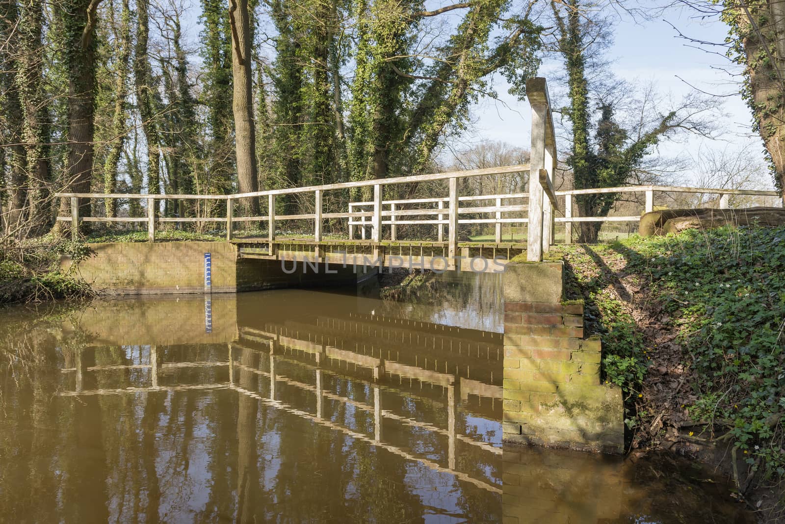 Old rundown wooden bridge over the brook the Boven-Slinge near Winterswijk in the Achterhoek in the early spring in the Netherlands
