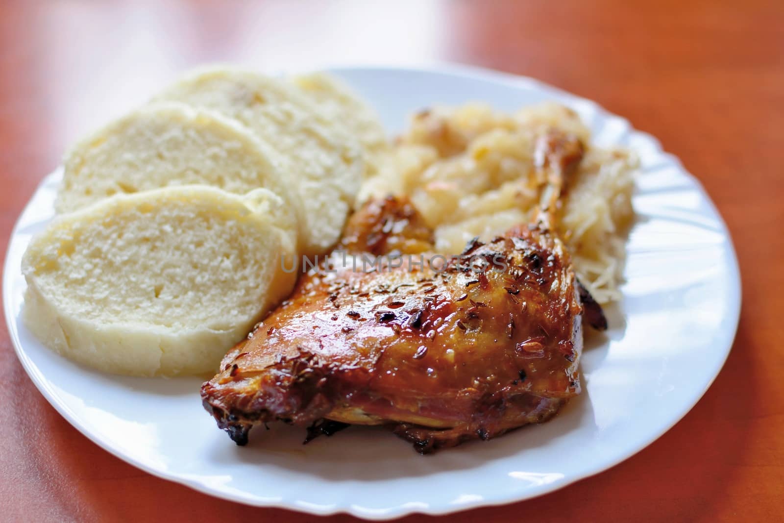 A Plate of Roast Duck Drumstick with Dumplings and Stewed White Cabbage.