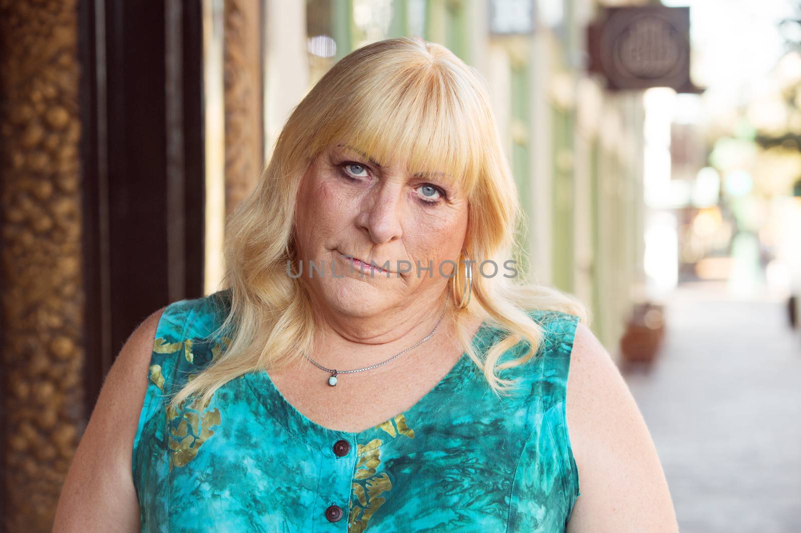 Skeptical blond middle aged transgender woman in blond hair and green dress