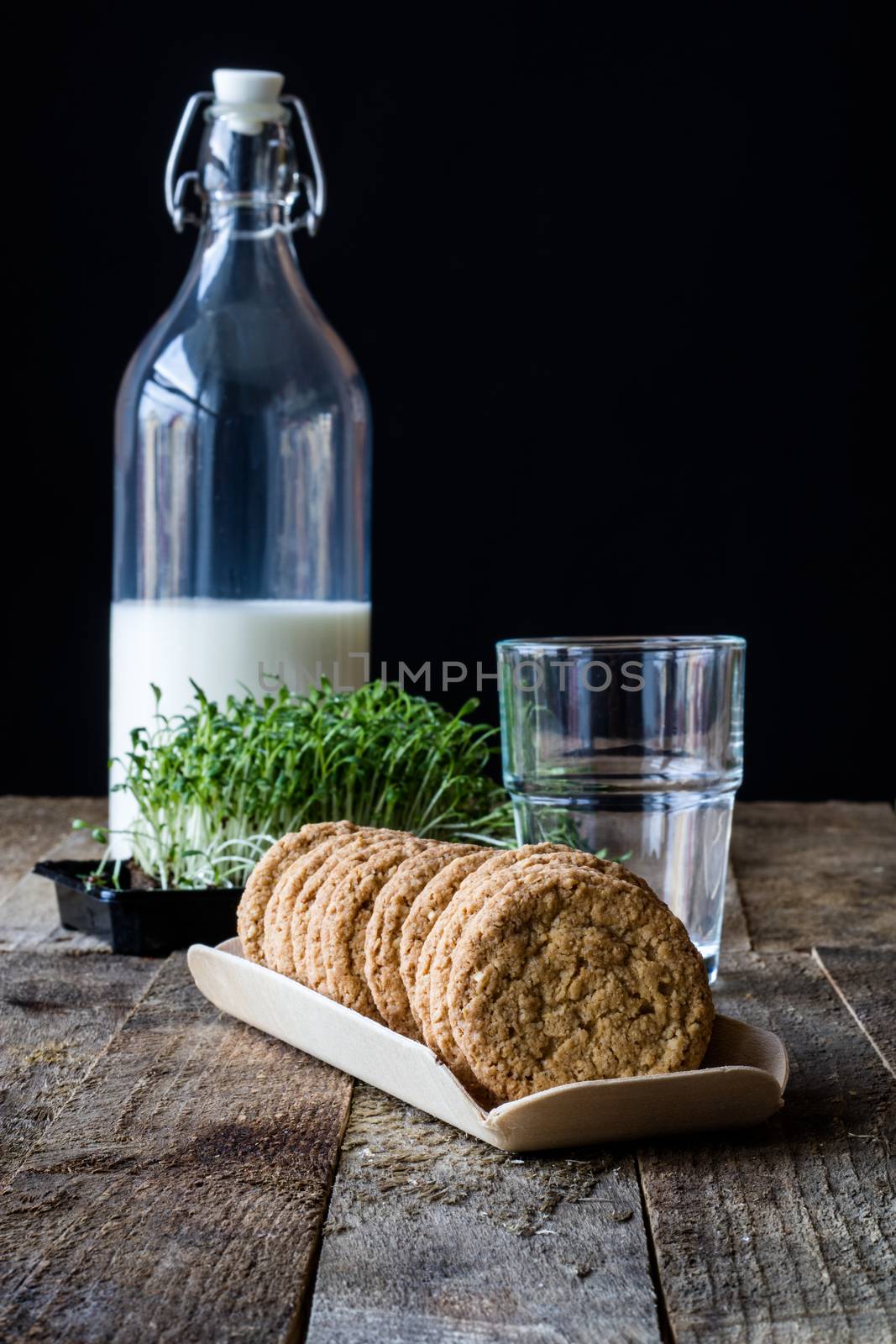 Milk and chocolate cookies on an old wooden table, black background