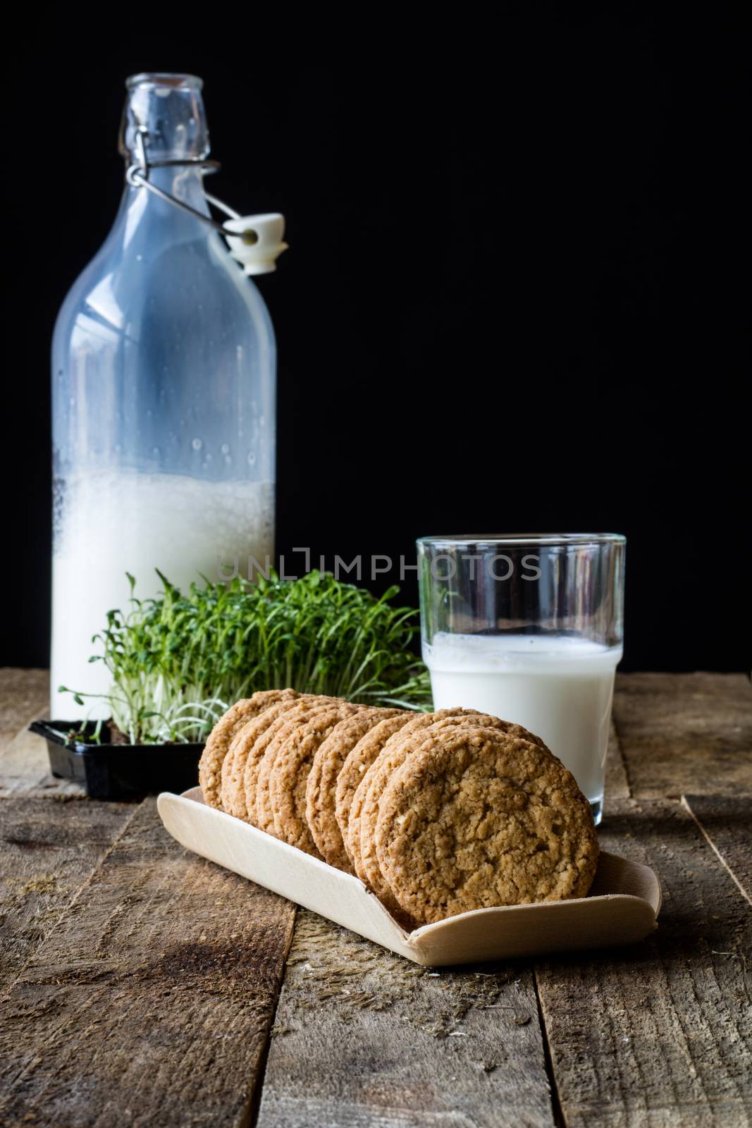 Milk and chocolate cookies on an old wooden table, black background