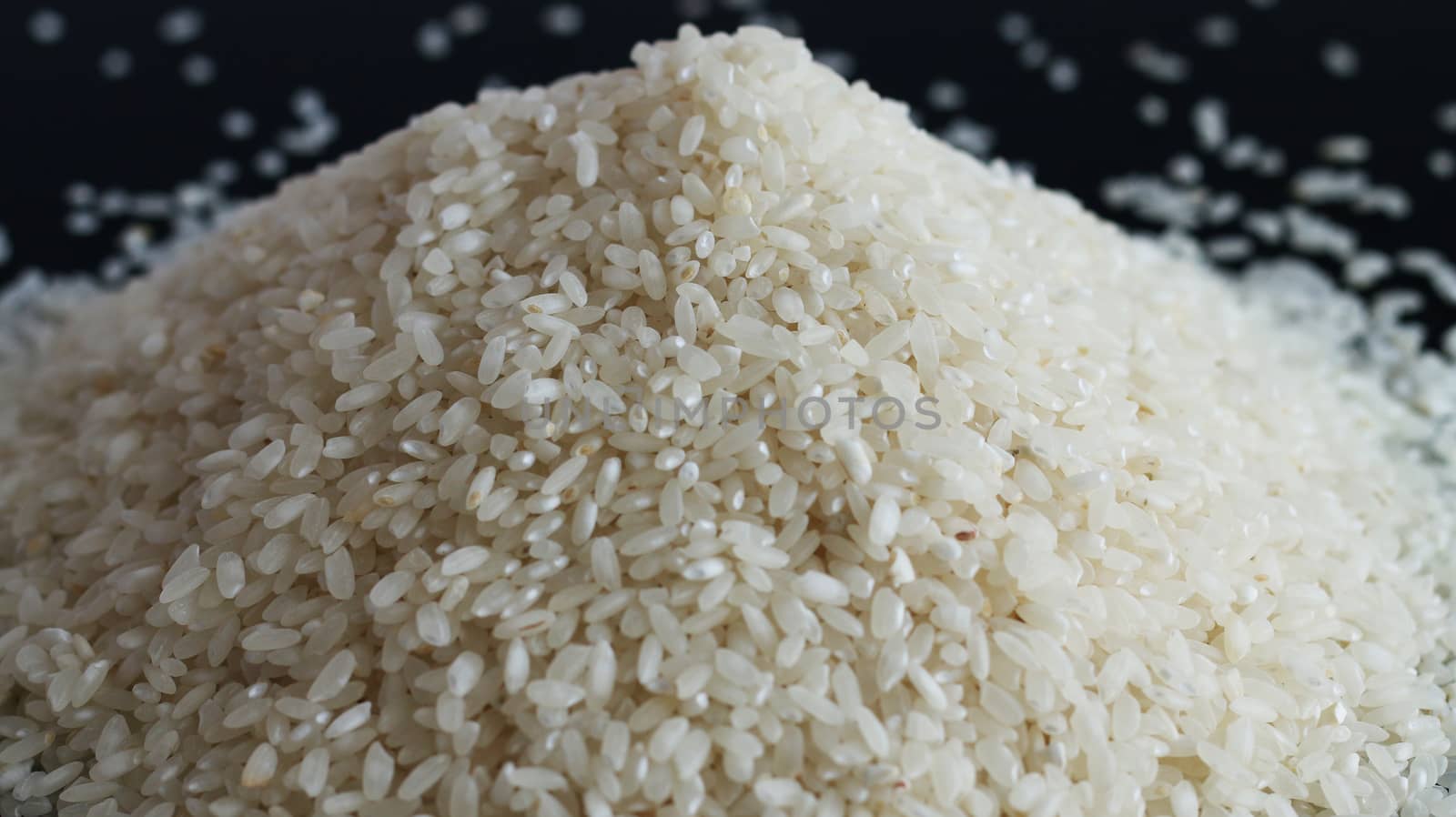 Pile of rice or wholegrain spill on black background. Agriculture food raw seed. Closeup macro photo