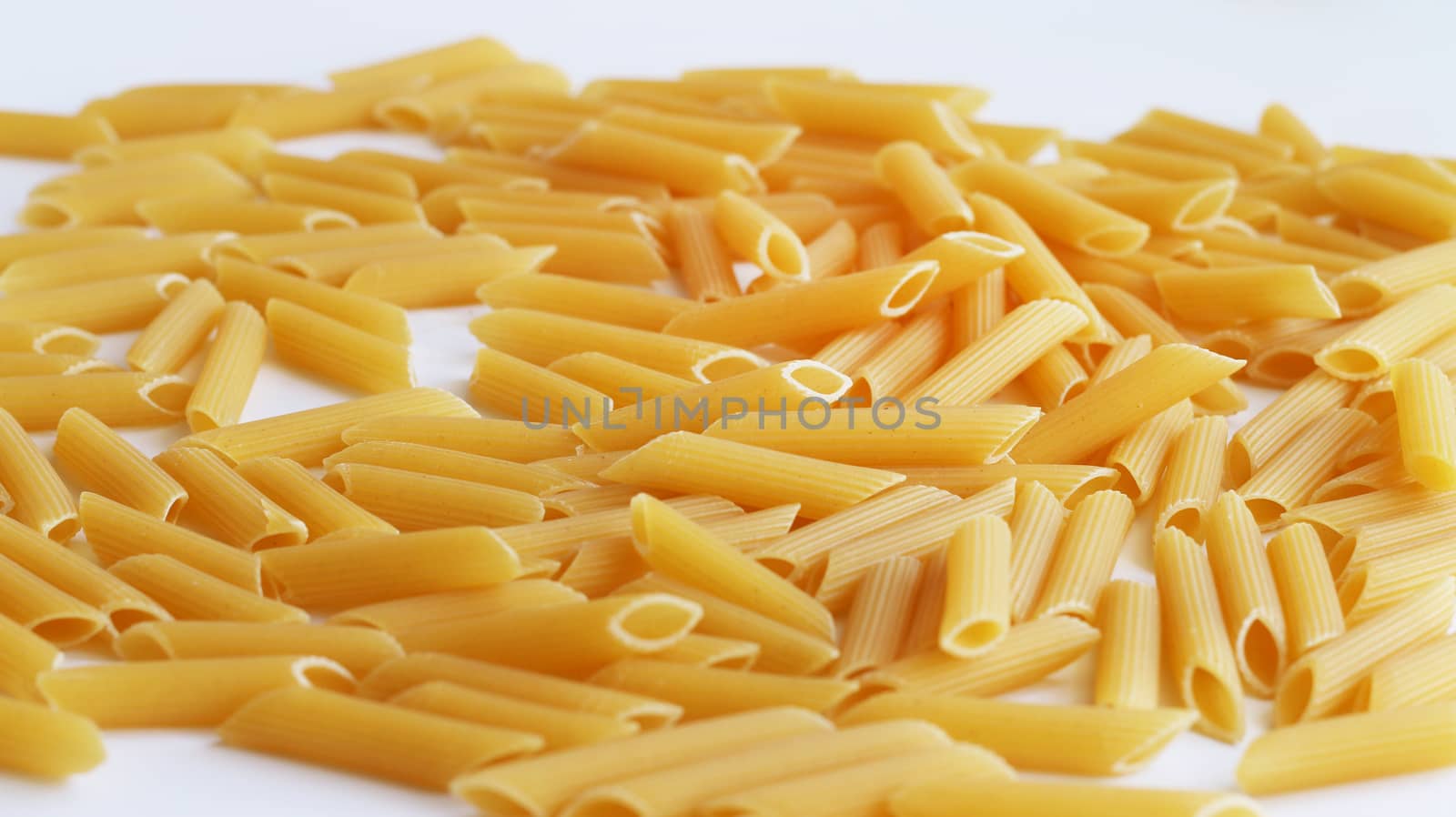 Spill tube pasta on white background. Raw uncooked food