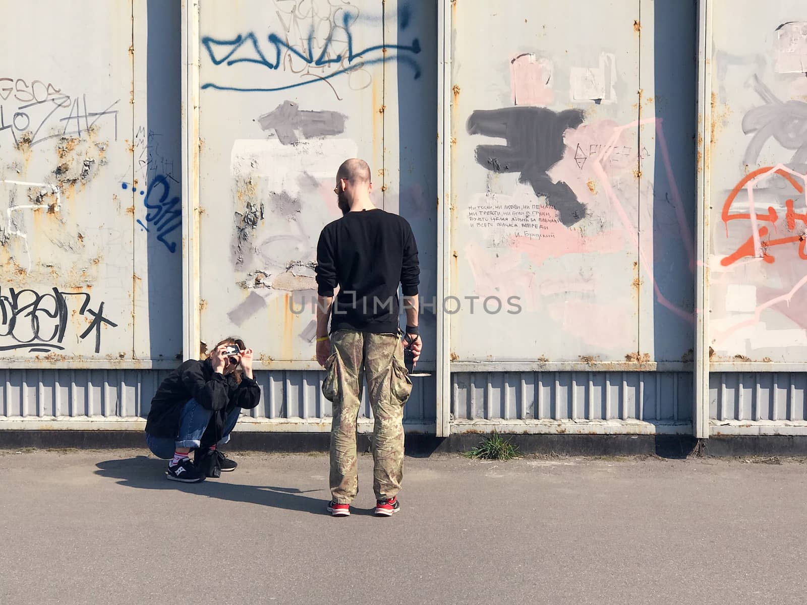 Happy couple taking a picture on a wall background with graffiti