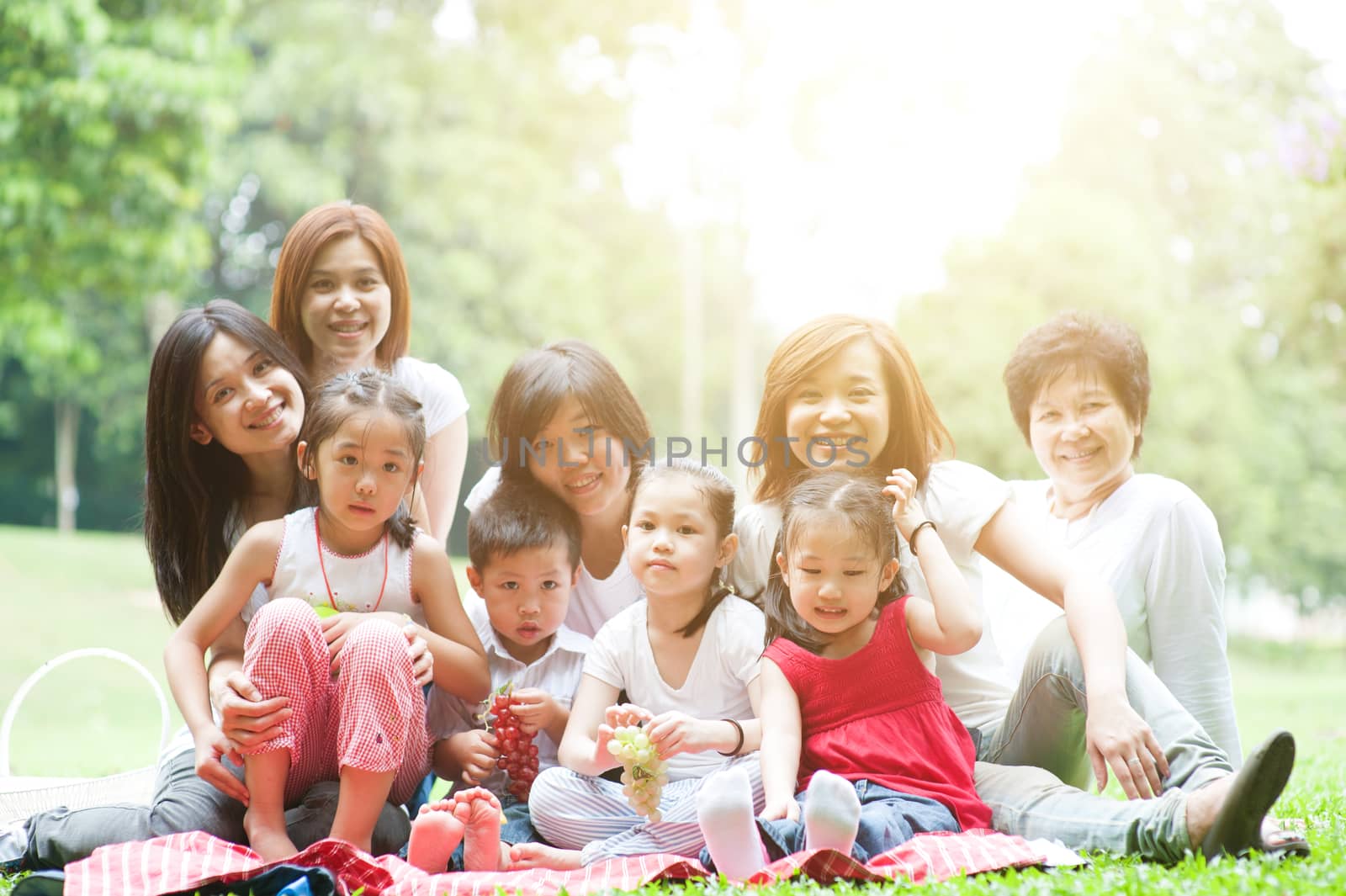 Beautiful Asian multi generations family portrait, grandparent, parents and children, outdoor nature park in morning with sun flare.