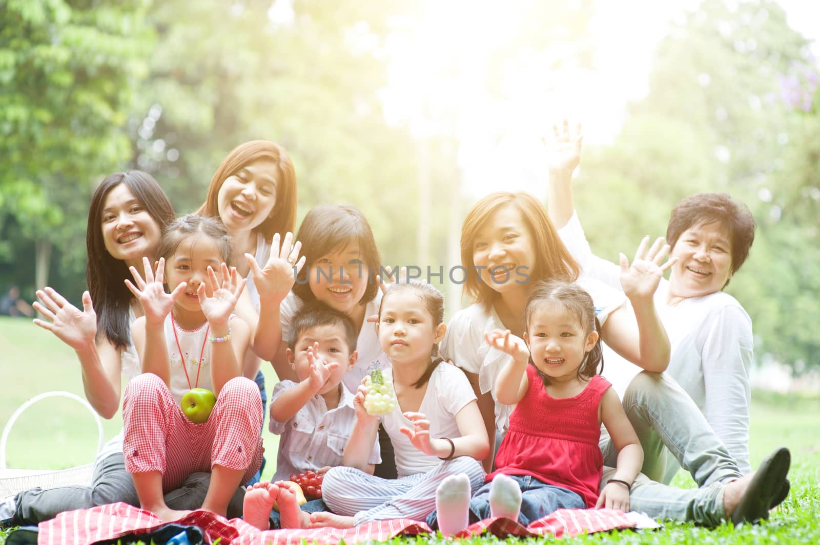 Group of Asian multi generations family portrait, grandparent, parents and children, outdoor nature park in morning with sun flare.