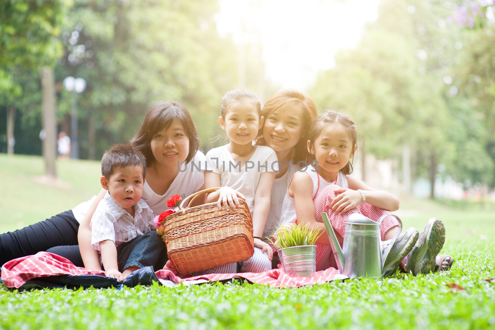 Happy Asian family portrait at nature park, morning outdoor with sun flare.