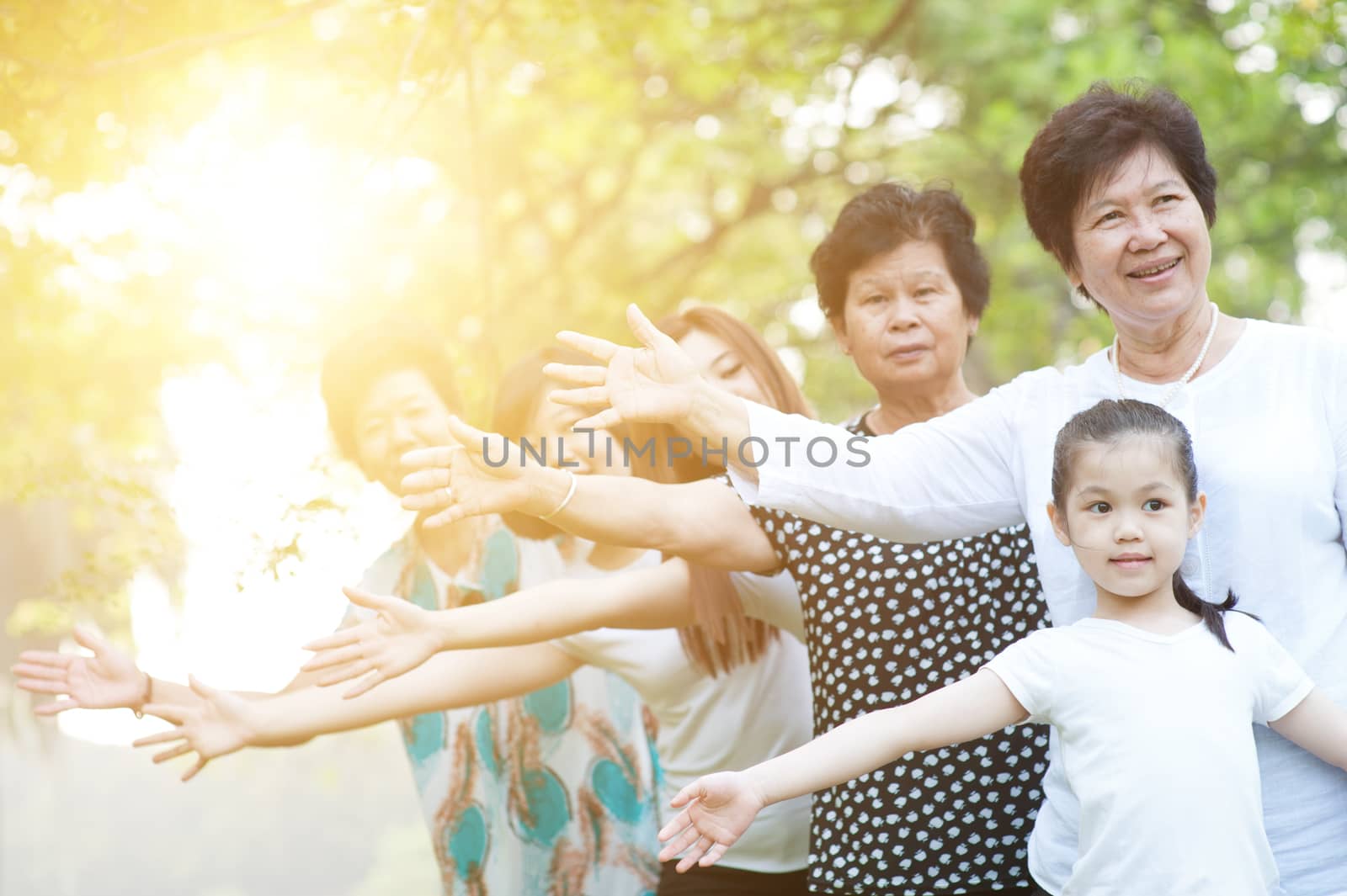 Big group of cheerful Asian multi generations family playing at park, grandparent, parent and children, outdoor nature park in morning with sun flare.