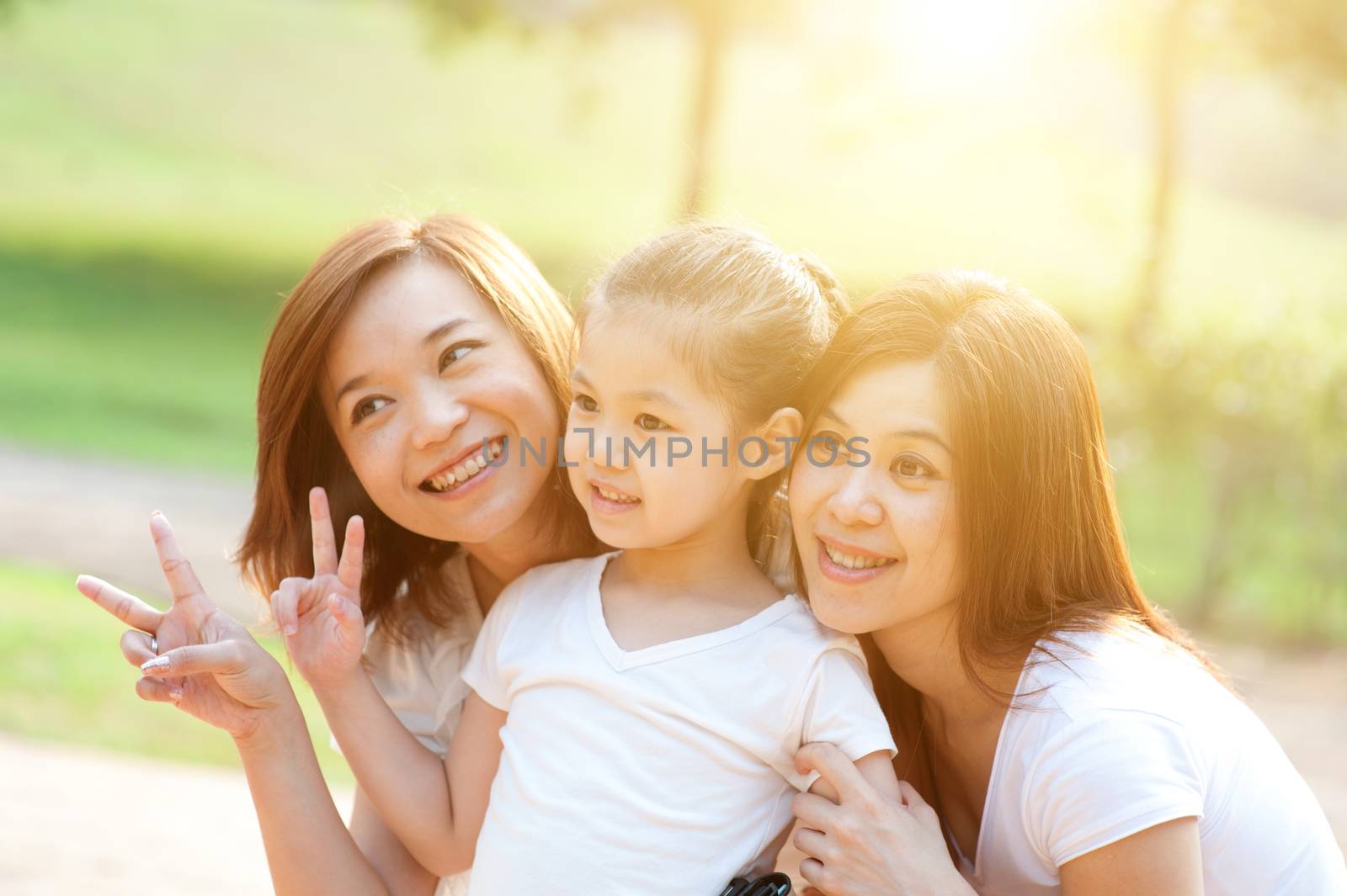 Asian family portrait at nature park, morning outdoor with sun flare.