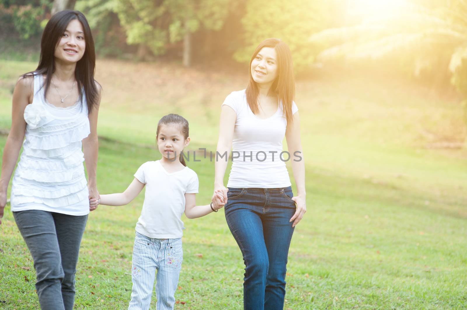 Asian family walking at nature park, morning outdoor with sun flare.