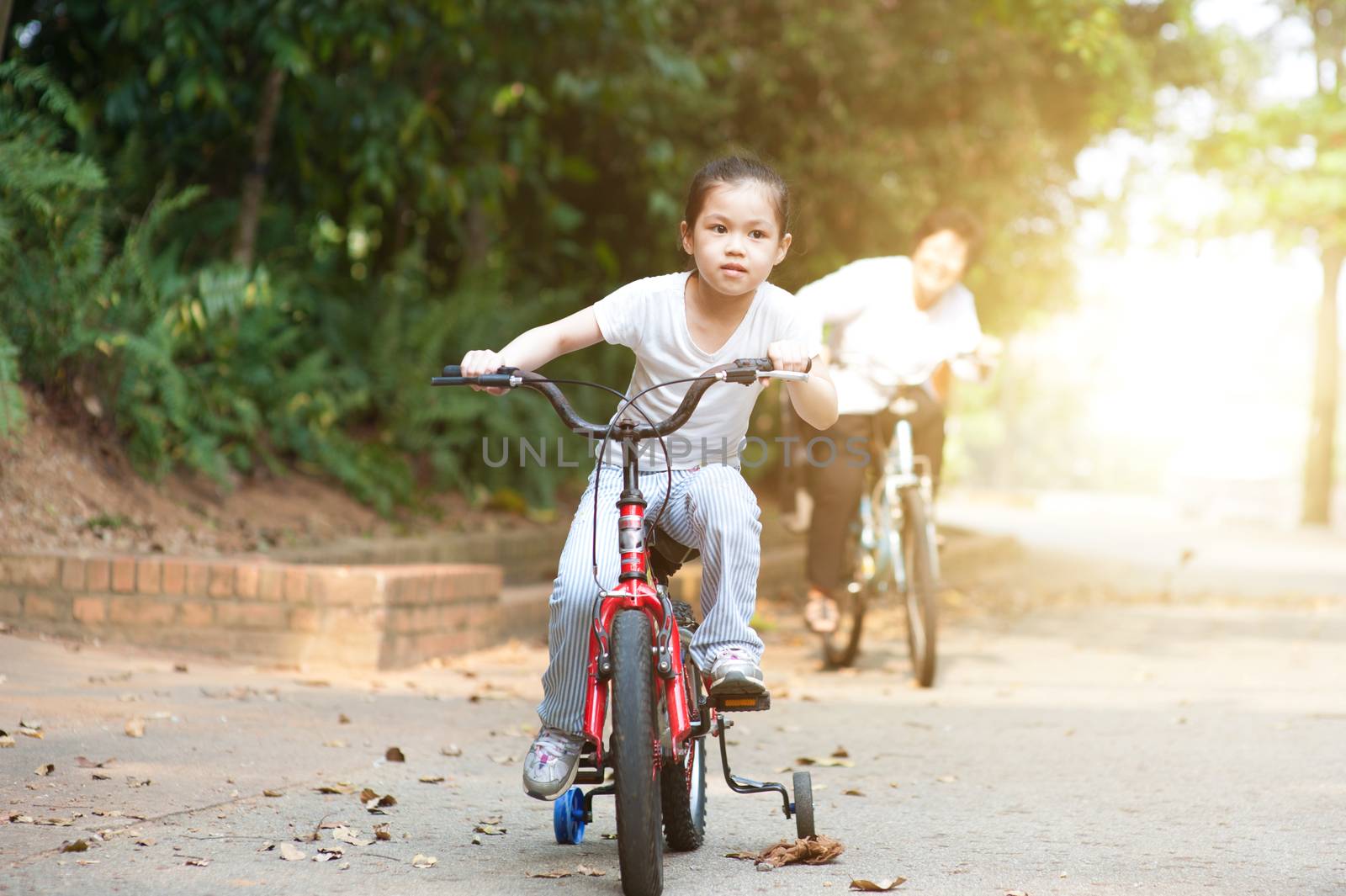 Grandmother and granddaughter riding bike outdoor. by szefei