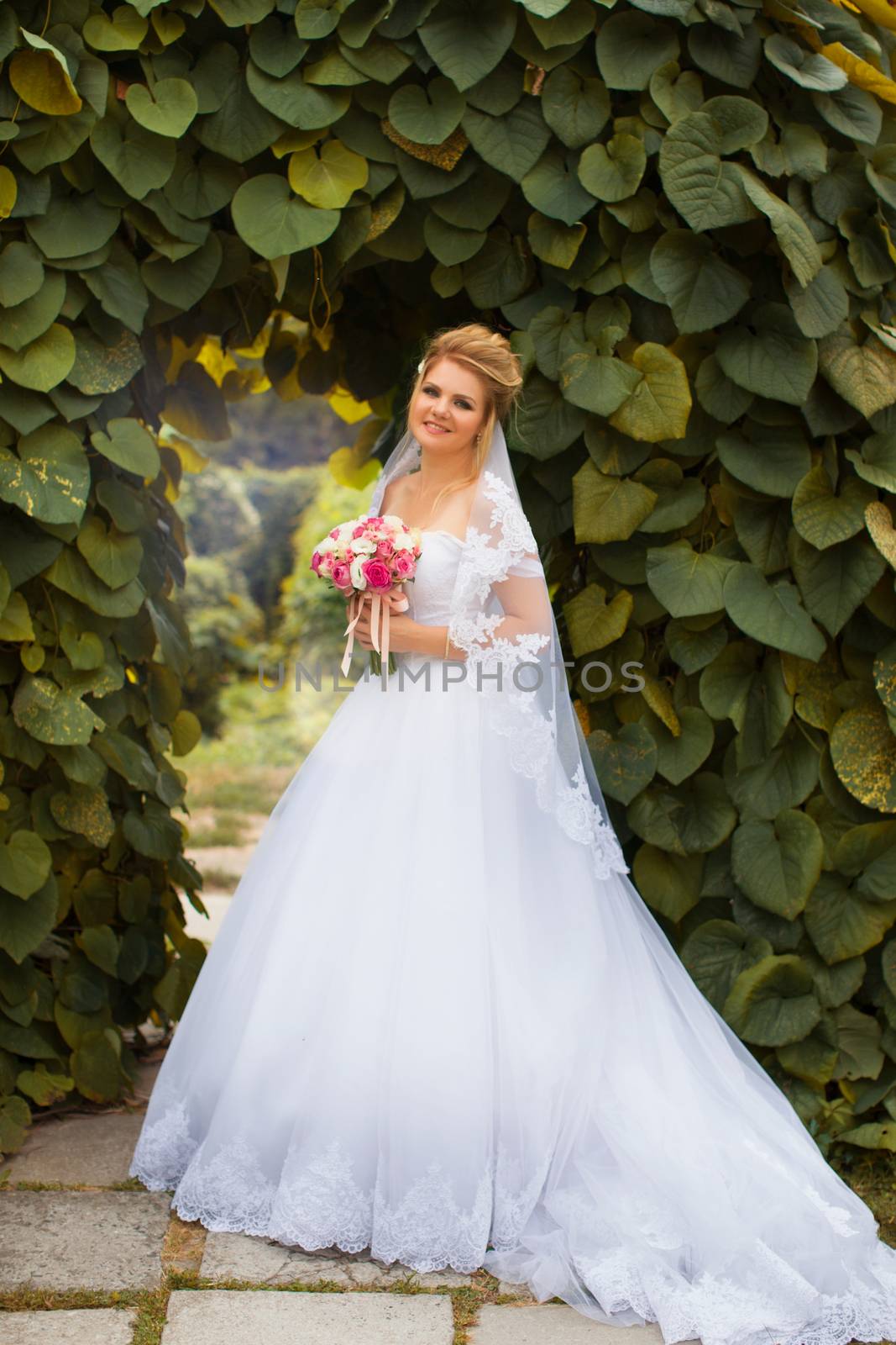 Stylish bride in a white wedding dress in summer day
