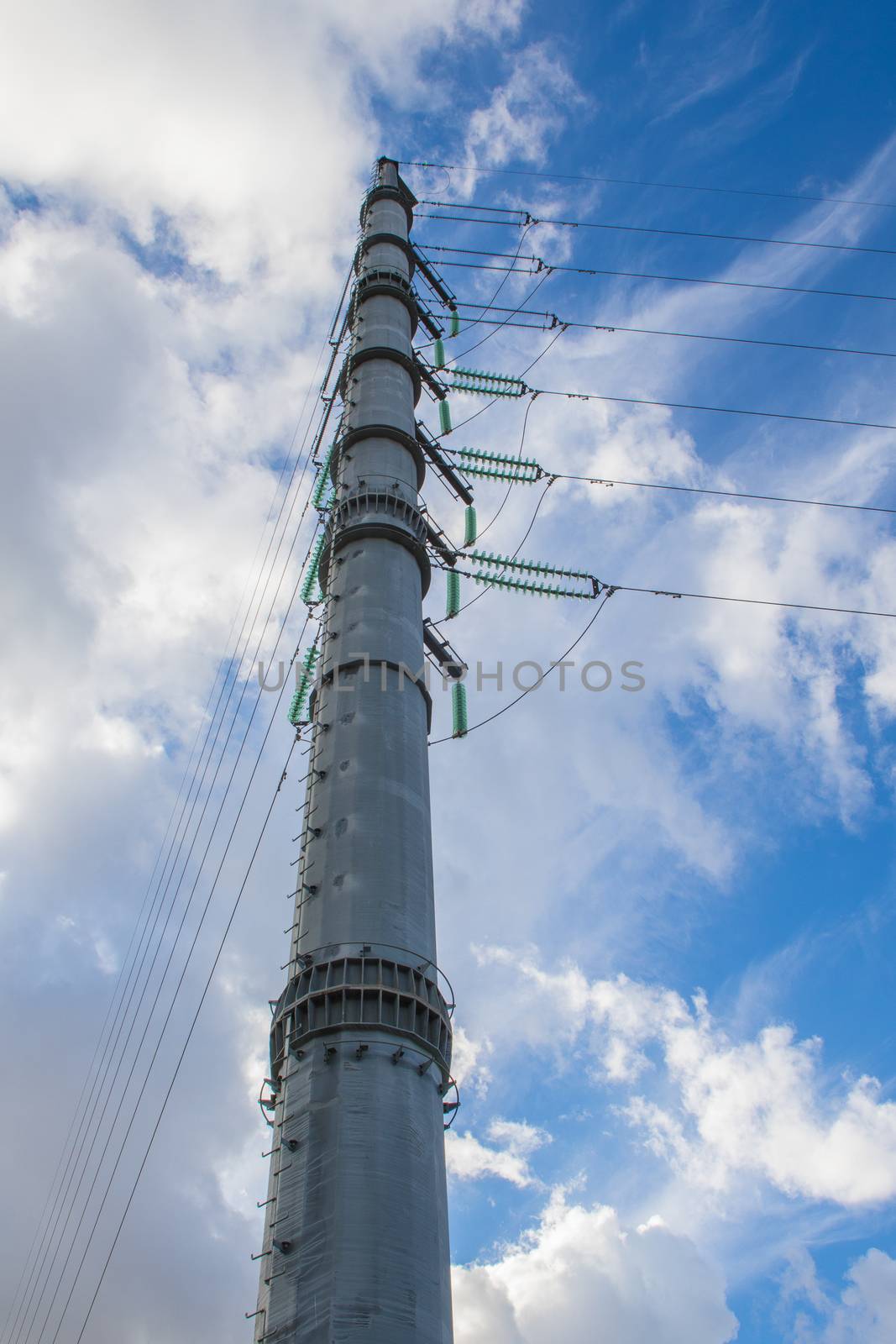 High-voltage power lines and insulators over blue sky background