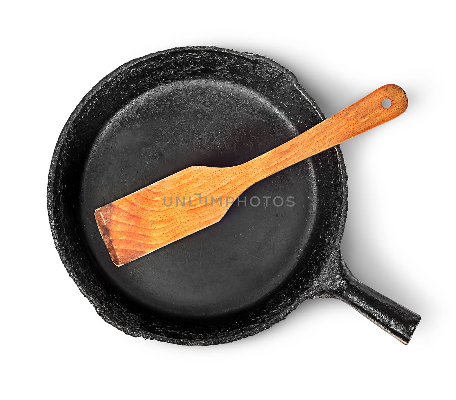 Old cast iron pan with wooden spatula top view by Cipariss