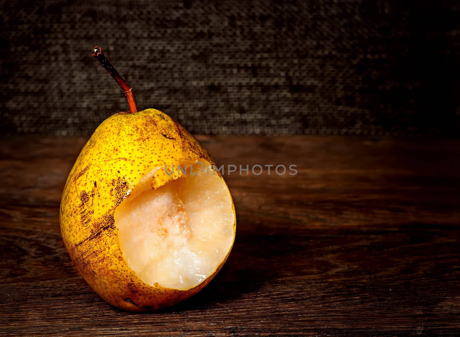 One bitten pear on a wooden table by Cipariss