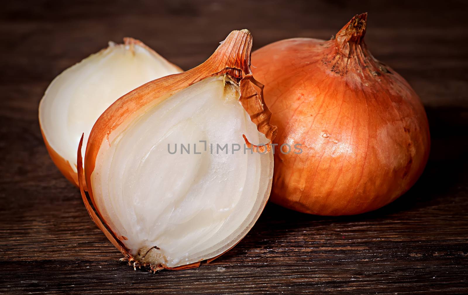 Wholly onion and two halves on a wooden table