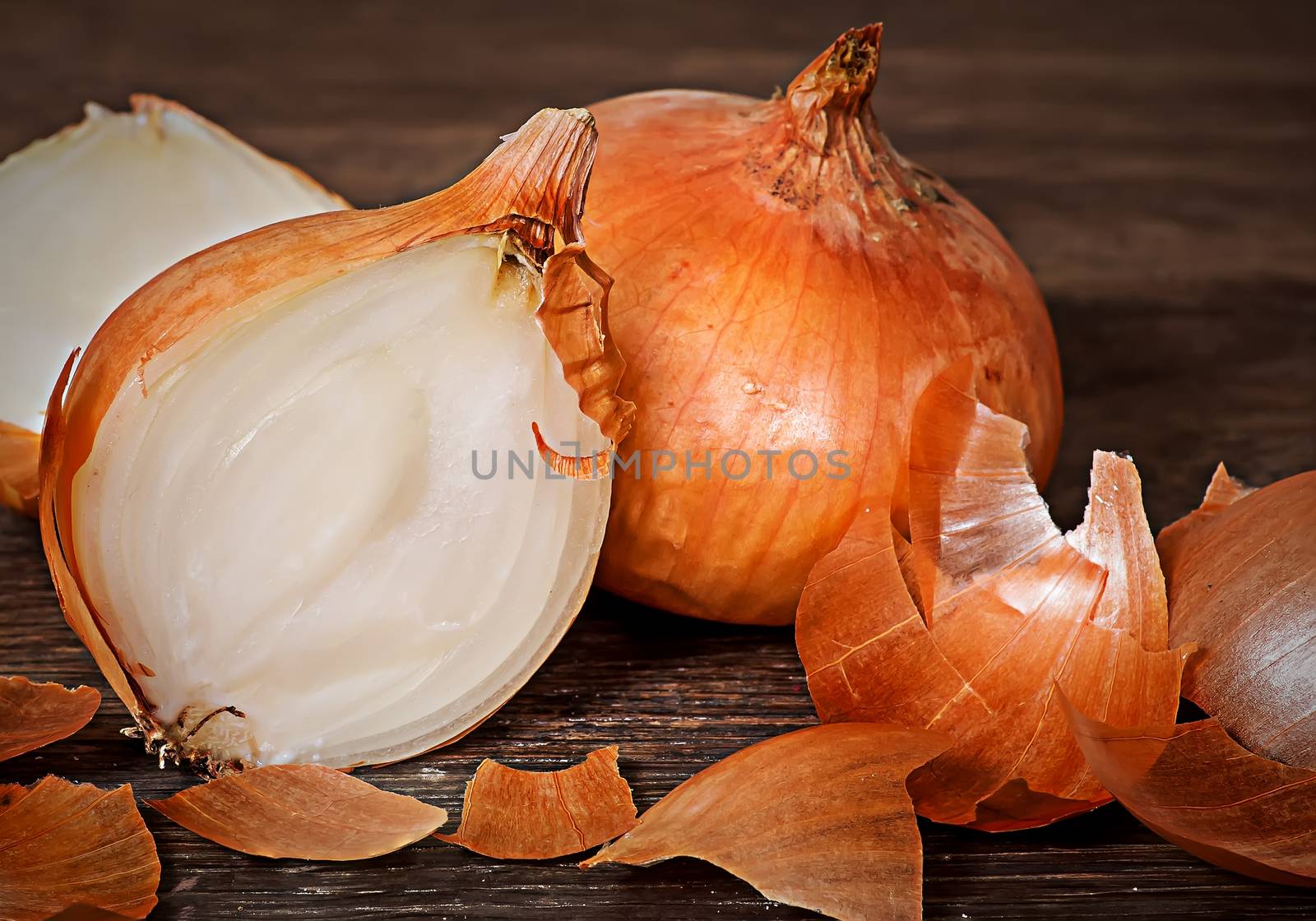 Onion bulbs with husks on wooden table