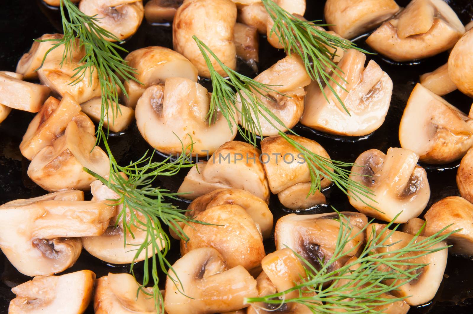 Quartered Roasted Champignons With Dill On A Black Frying Pan