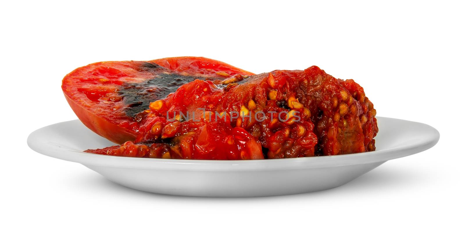 Rotting tomato on white plate isolated on white background