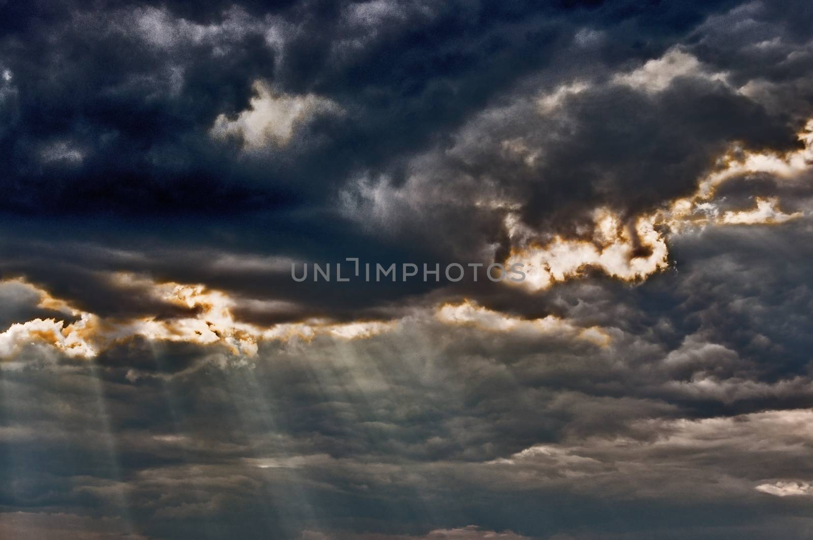 Dark stormy sky with a dramatic sunbeams