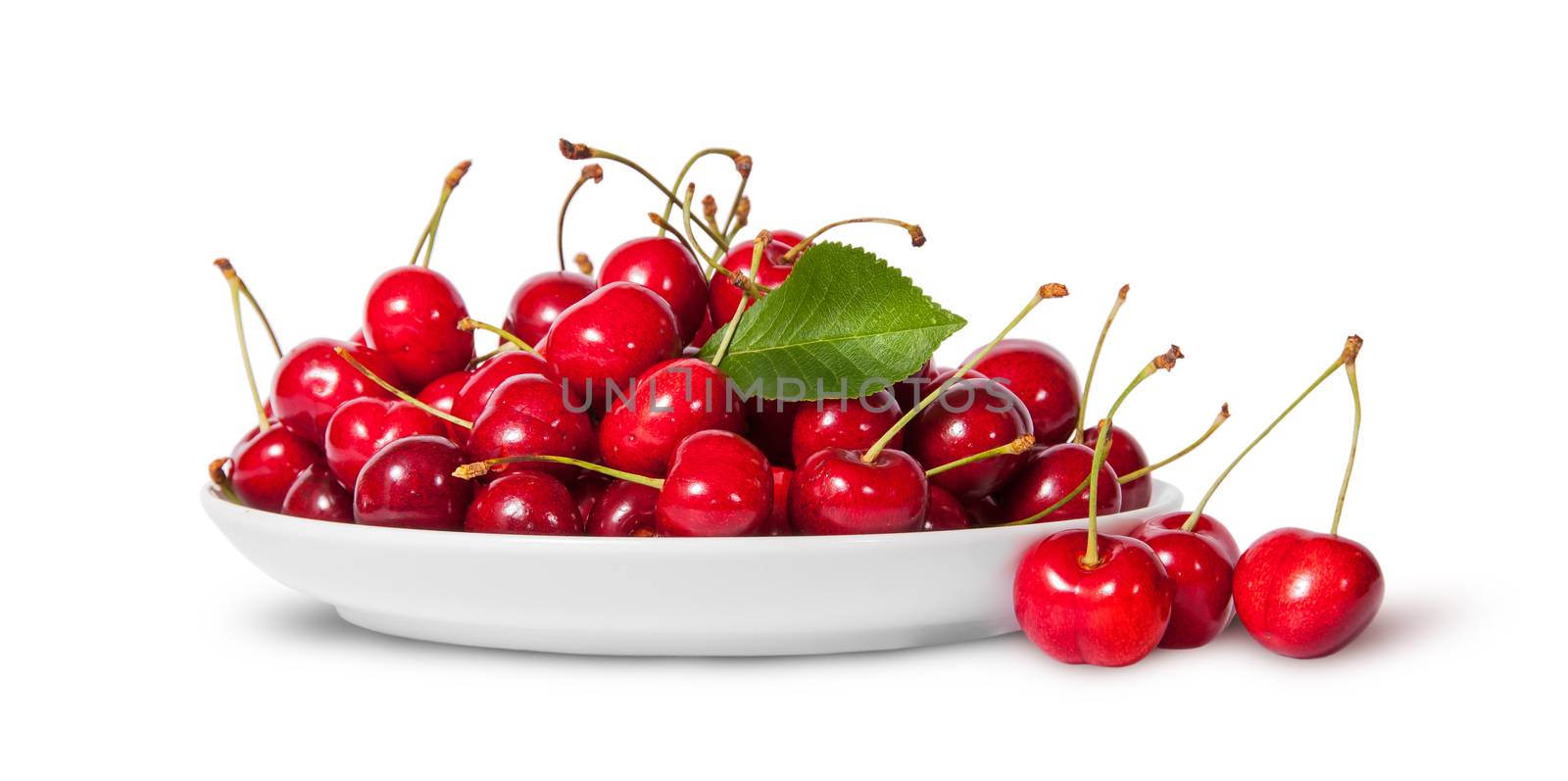 Sweet cherries with leaf on white plate and three near isolated on white background