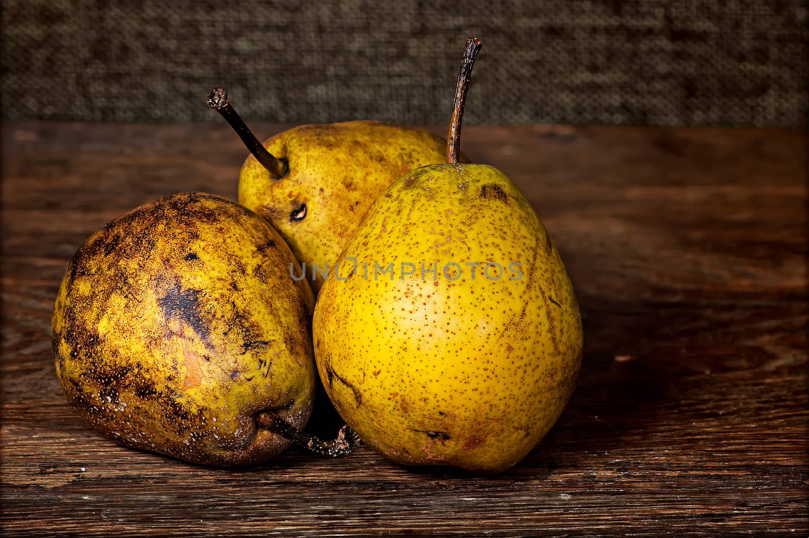 Three old pears on a wooden table by Cipariss