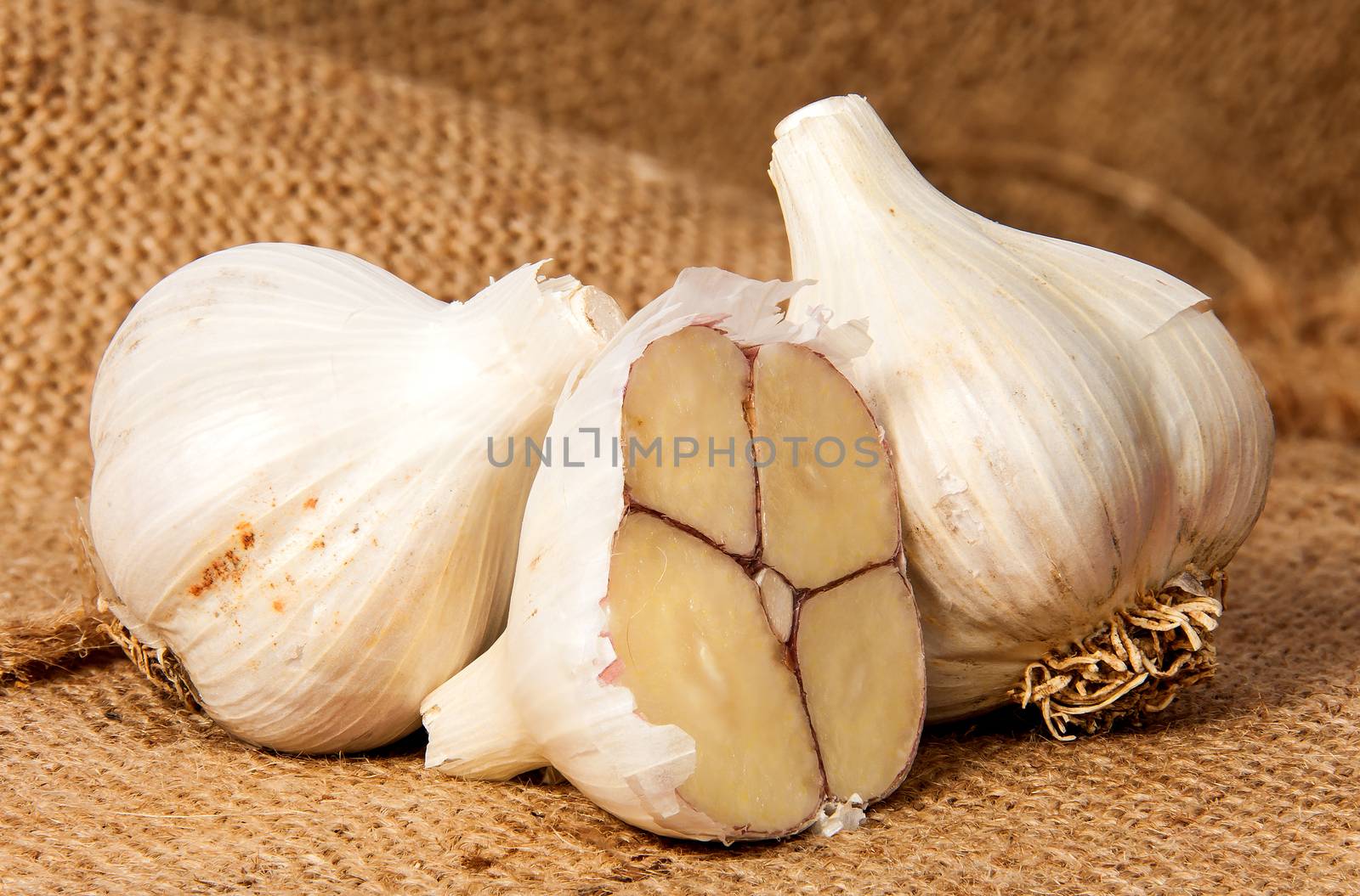 Two whole and half head of garlic on sackcloth