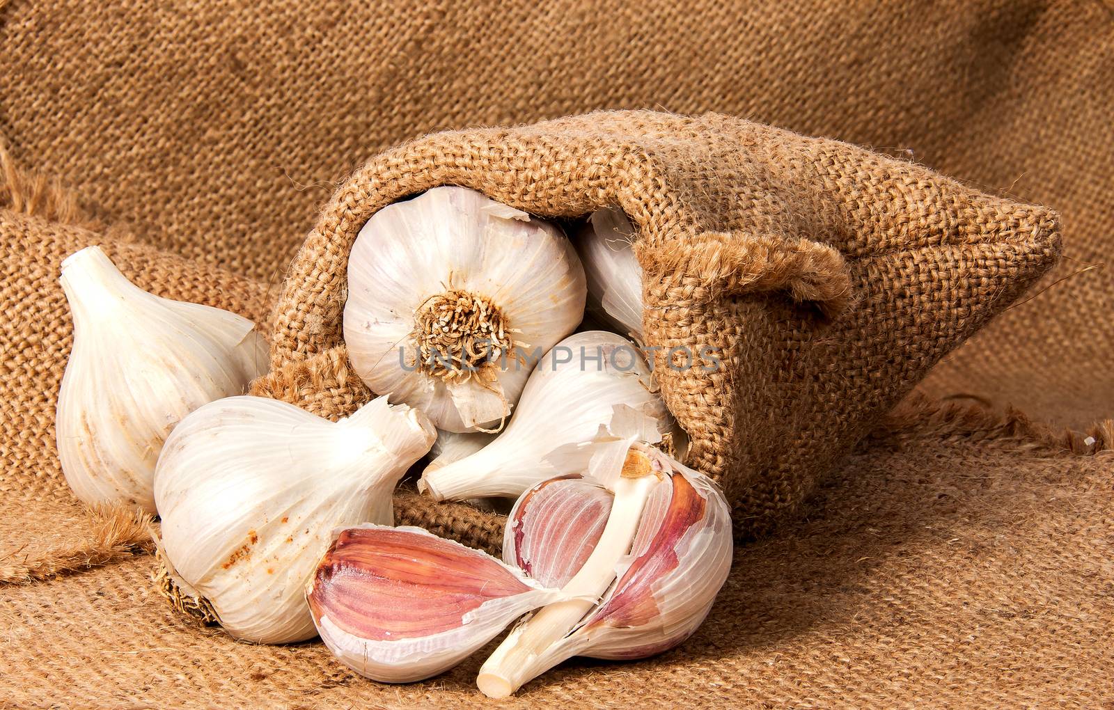 Whole garlic and cloves of garlic in a bag on sacking
