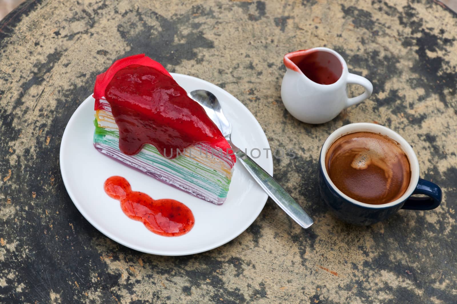 crepe cake rainbow and hot espresso coffee in garden side home. crape cake with strawberry sauce