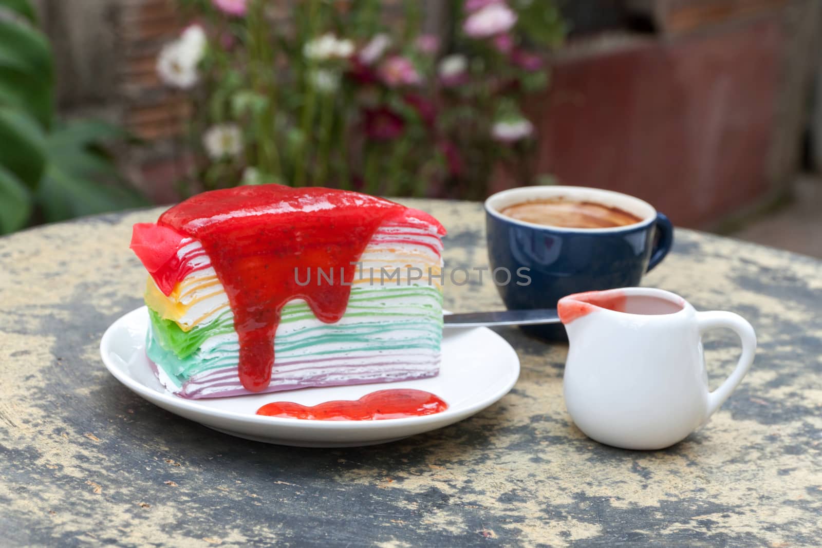 crepe cake rainbow and hot espresso coffee in garden side home. crape cake with strawberry sauce