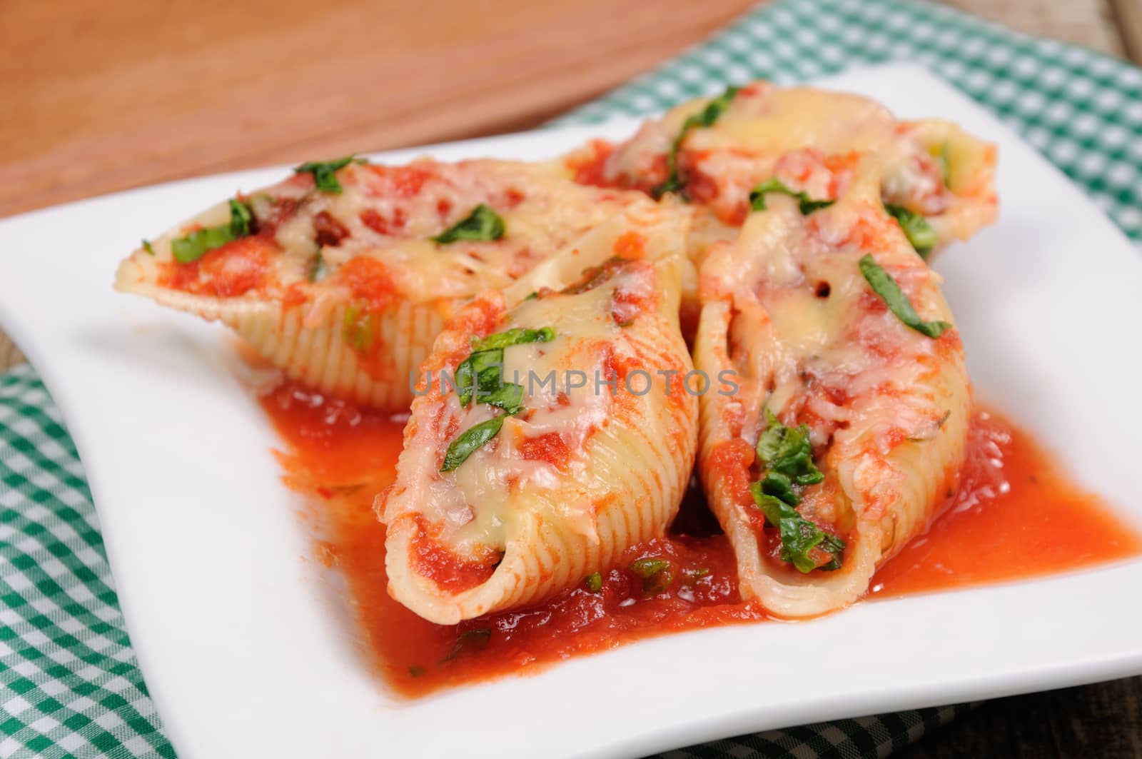pasta conchiglioni shells stuffed meat mince with spinach and tomato sauce , Parmesan cheese, on a plate. Front view. 