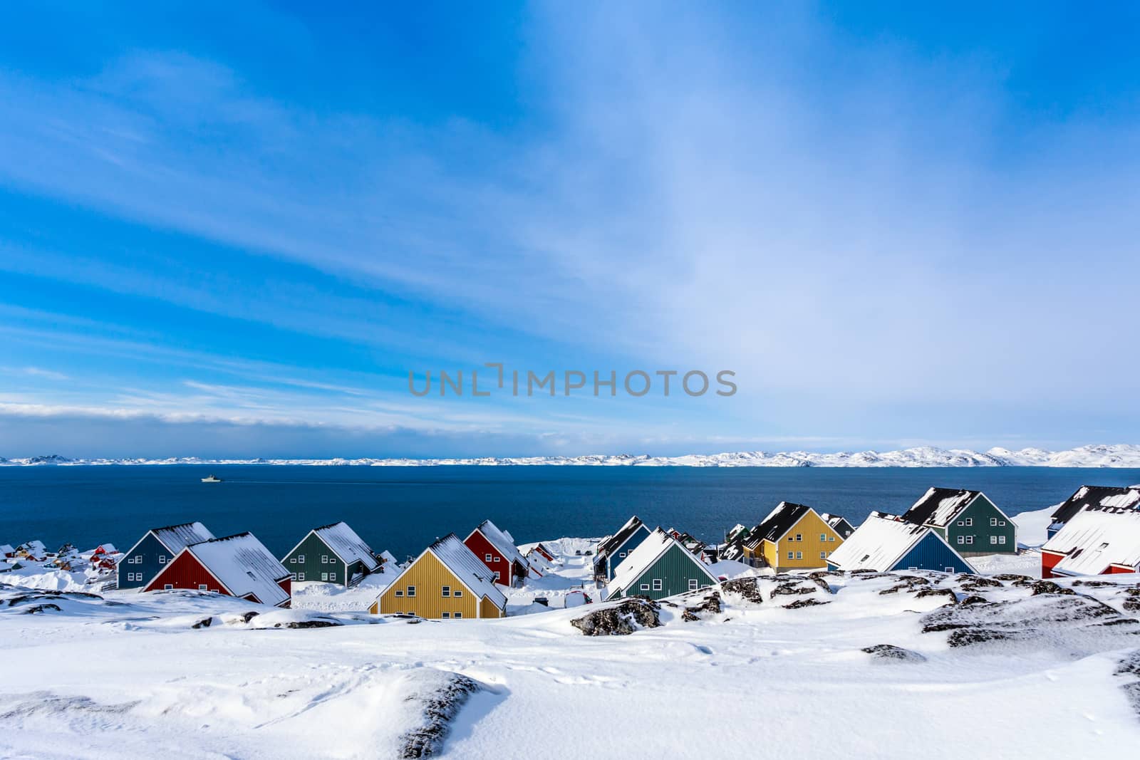 Yellow, blue, red and green inuit houses covered in snow at the  by ambeon
