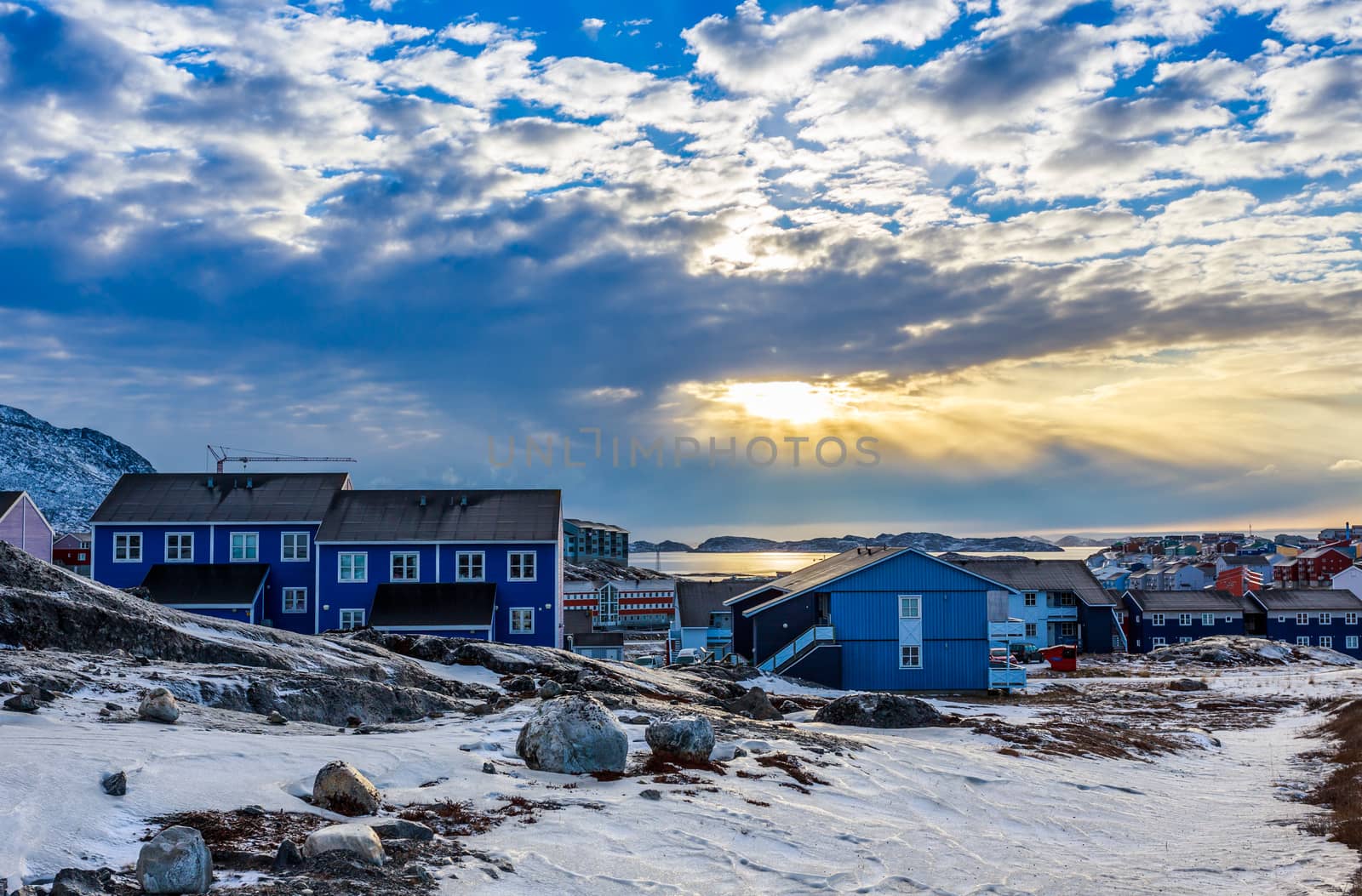 Polar sunset over Inuit houses on the rocky hills with snow, Nuu by ambeon