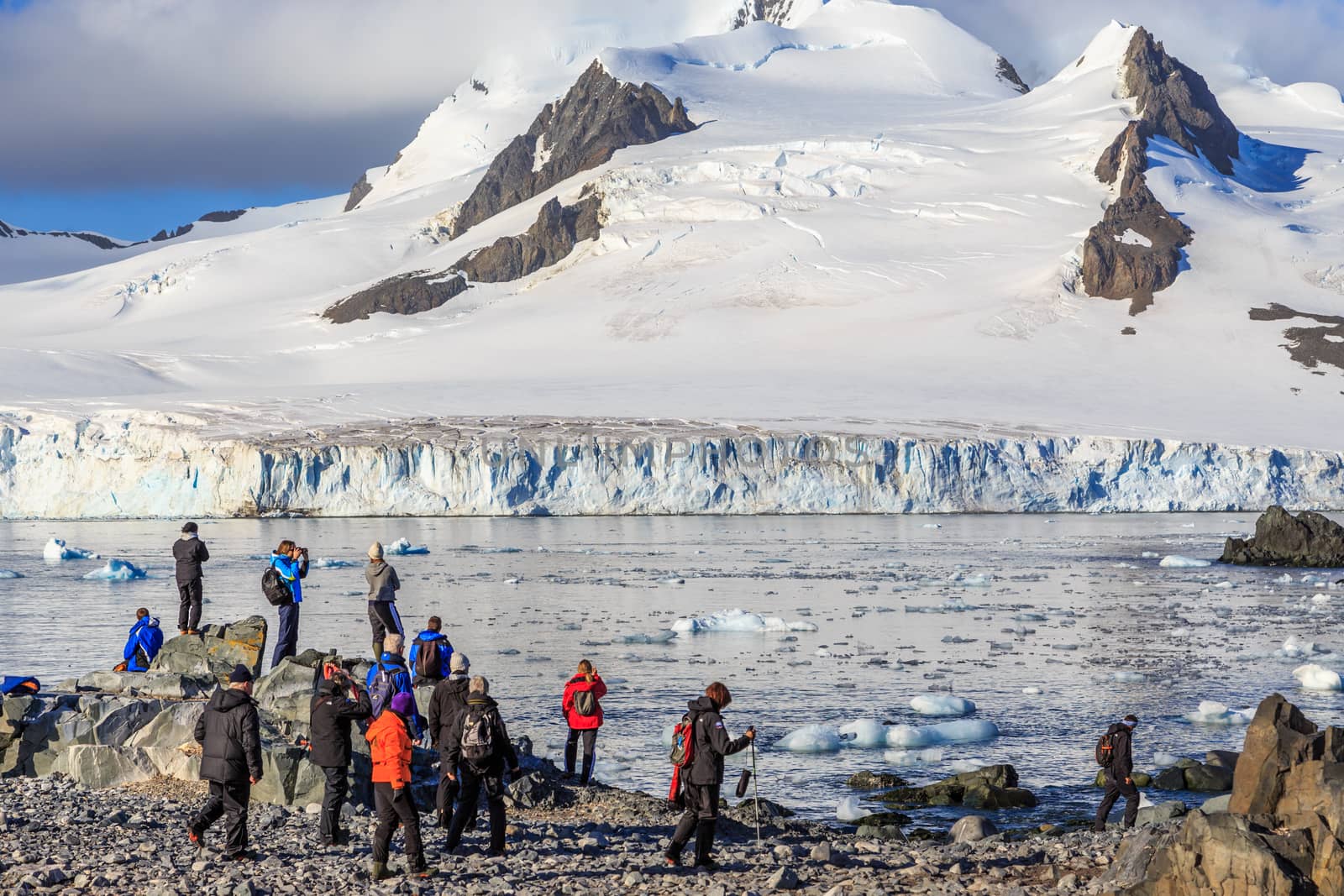 Group of tourists looking at the glacier at the stony shore of Half Moon Island, Antarctic