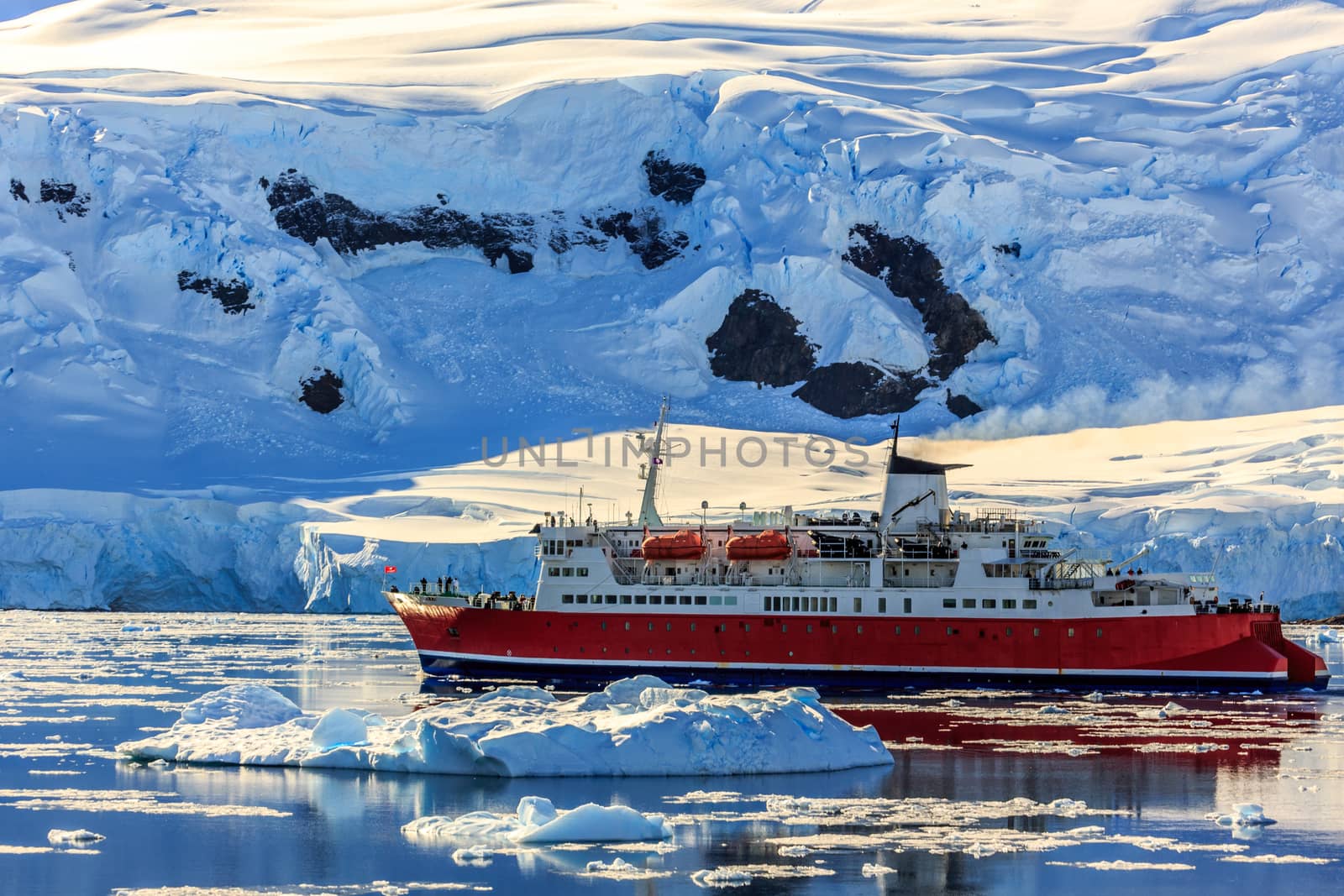 Red cruise steamboat among the icebergs with glacier in backgrou by ambeon