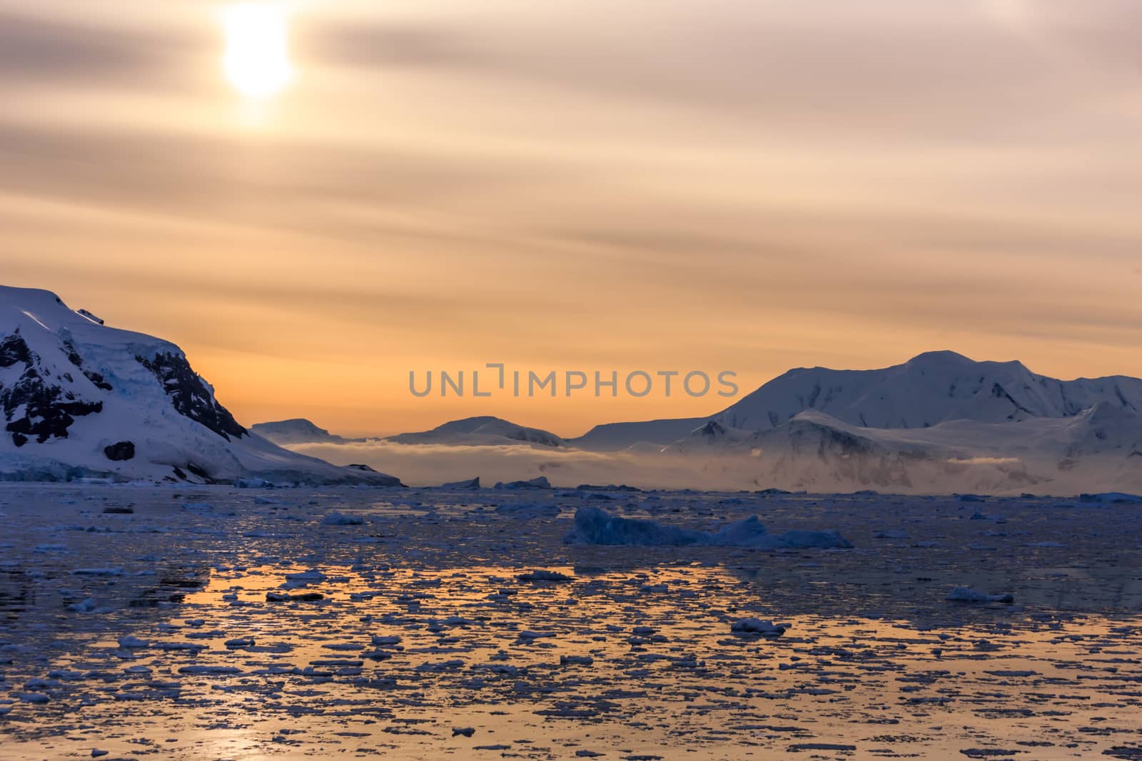 Sunset over the mountains and icebergs at Lemaire Strait, Antarctica