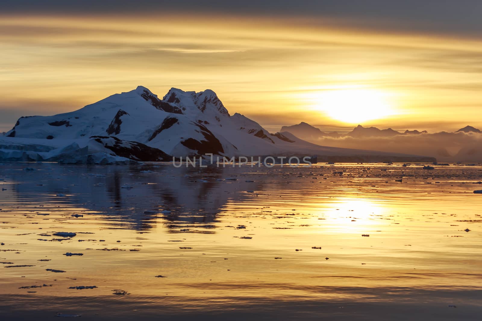 Sunset over the mountains and drifting icebergs at Lemaire Strait, Antarctica