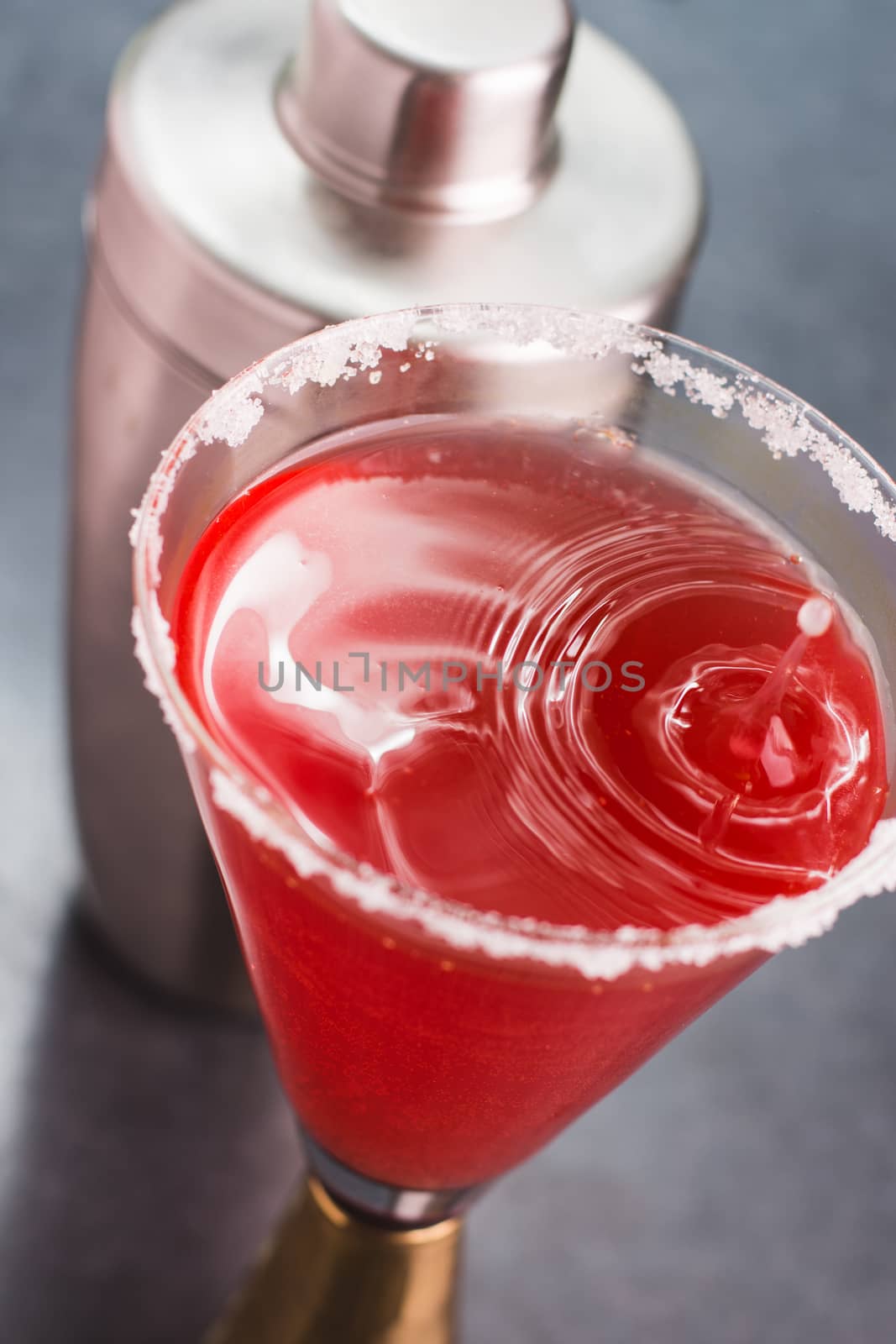 strawberry cocktail drink with droplet and shaker in the background