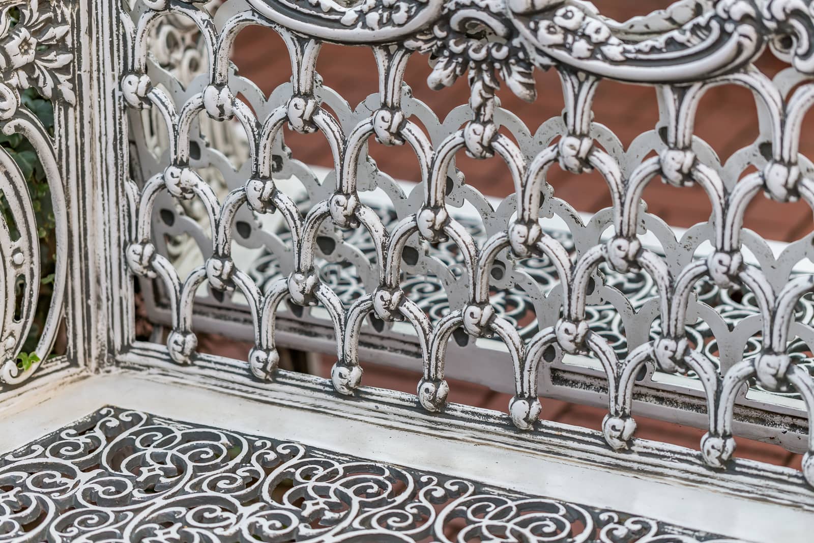 Pattern detail on a wrought iron bench in a park.