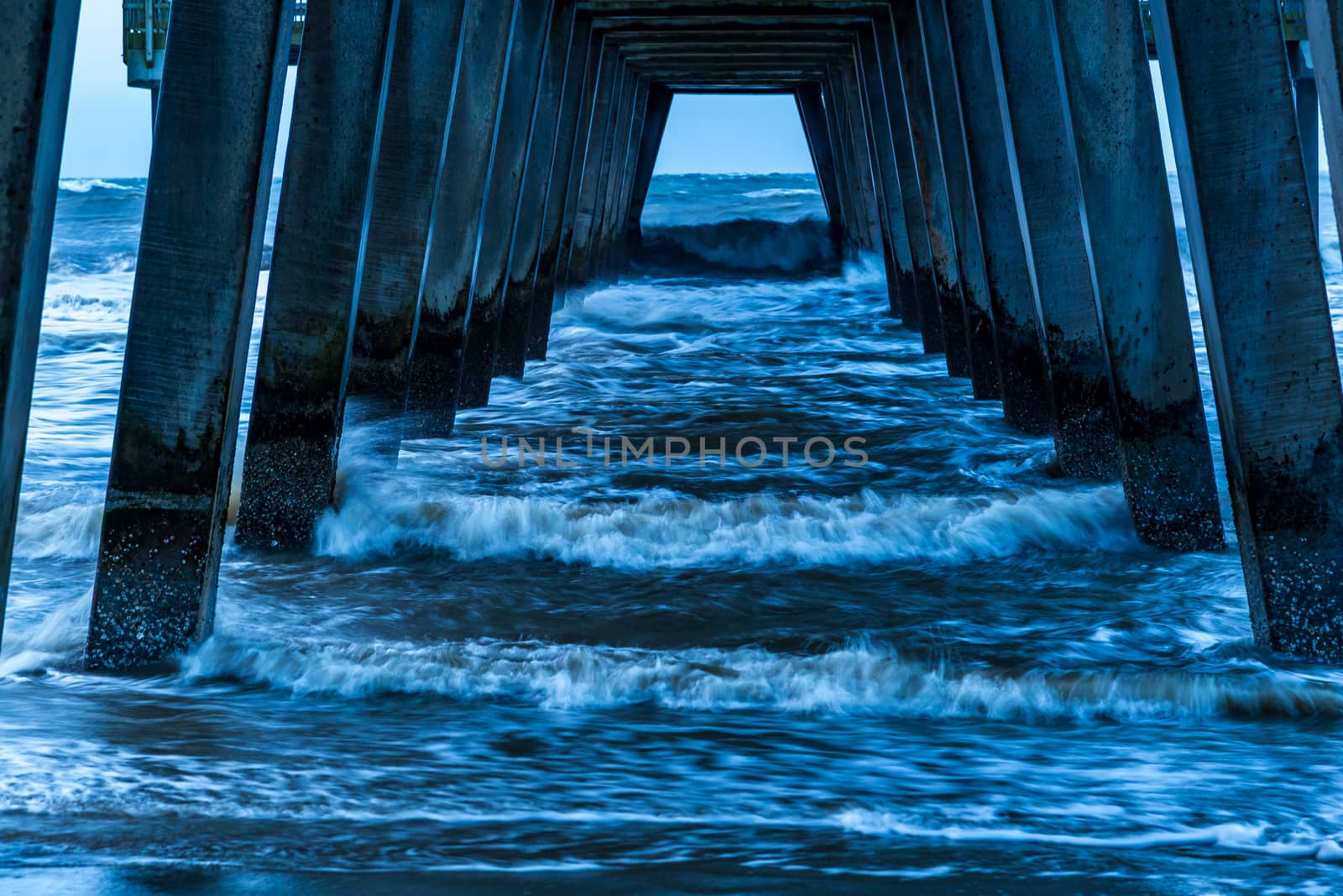 A stormy morning crashes ocean waves against the pier at Tybee Island, Georgia.