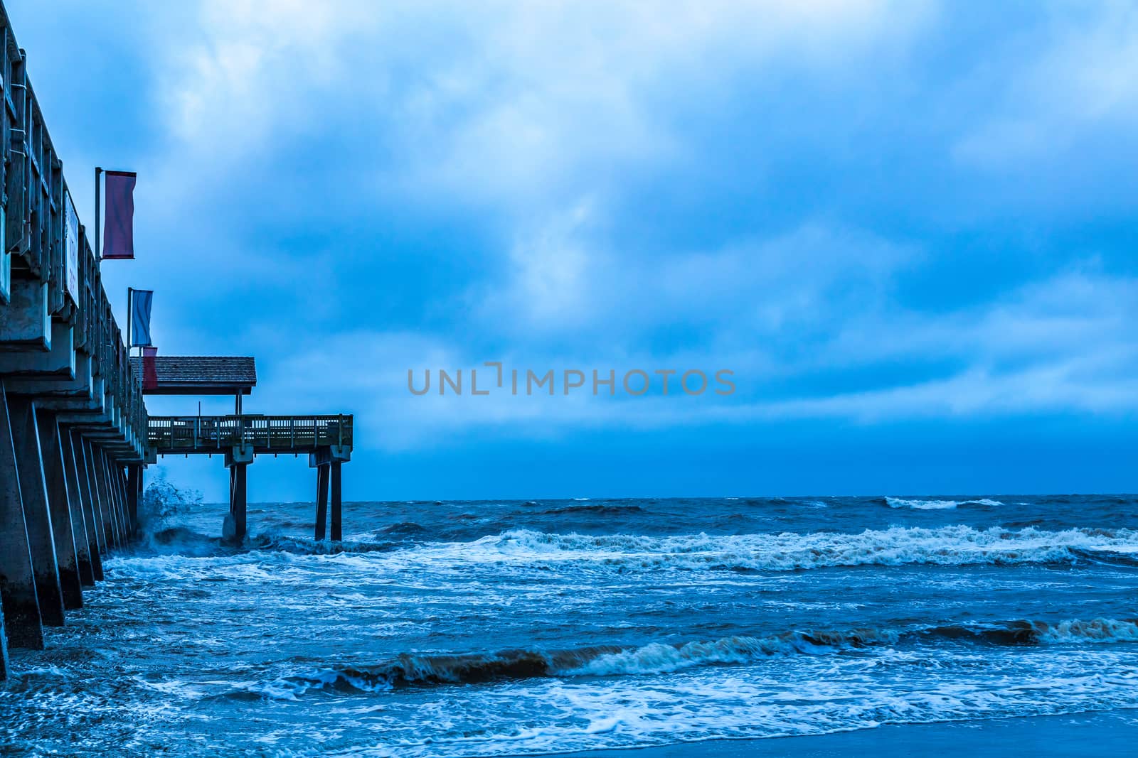 A stormy morning crashes ocean waves against the pier at Tybee Island, Georgia.