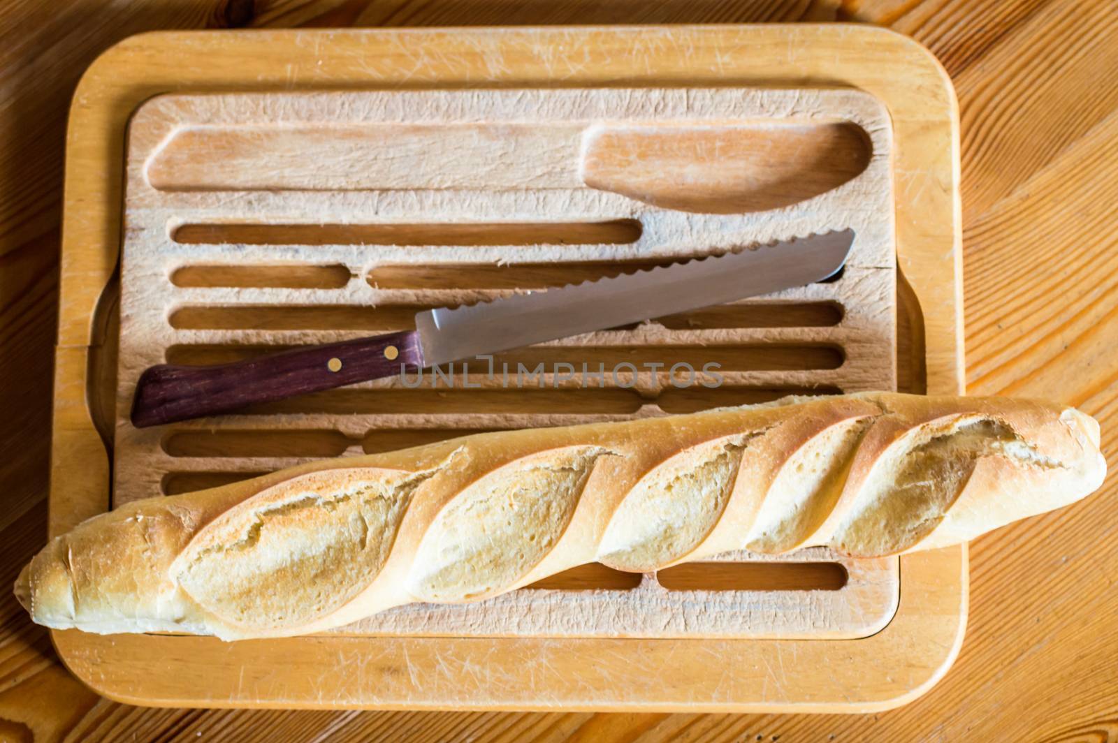 Close up french bread baguette on vintage wooden board with knife